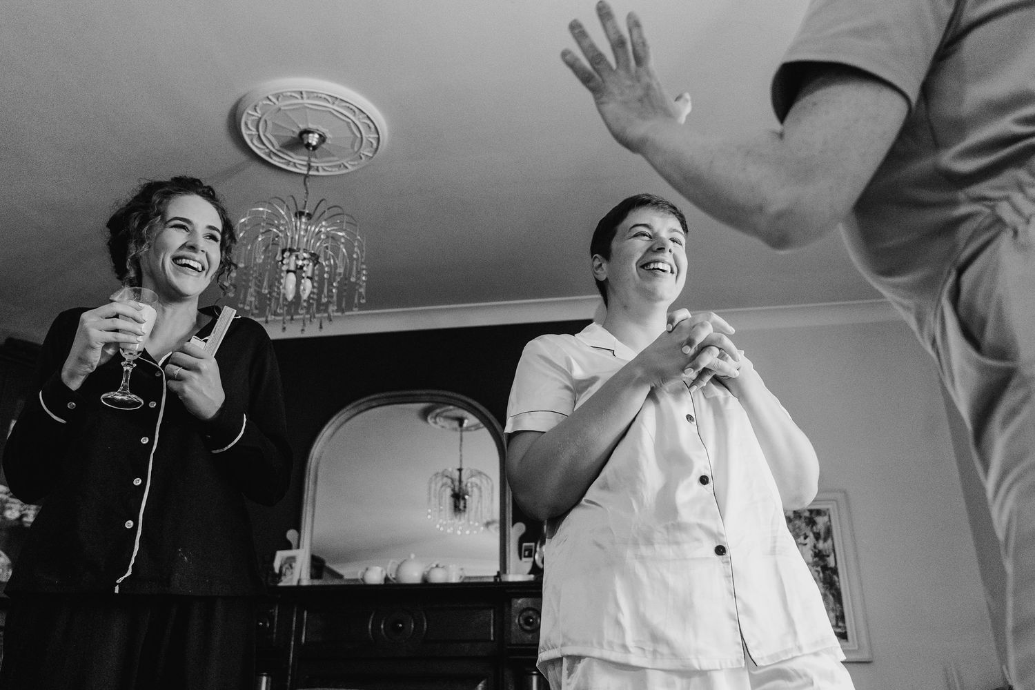 A vintage black and white photograph shows two people in white uniforms laughing and raising their hands during a social event.Millhouse sla