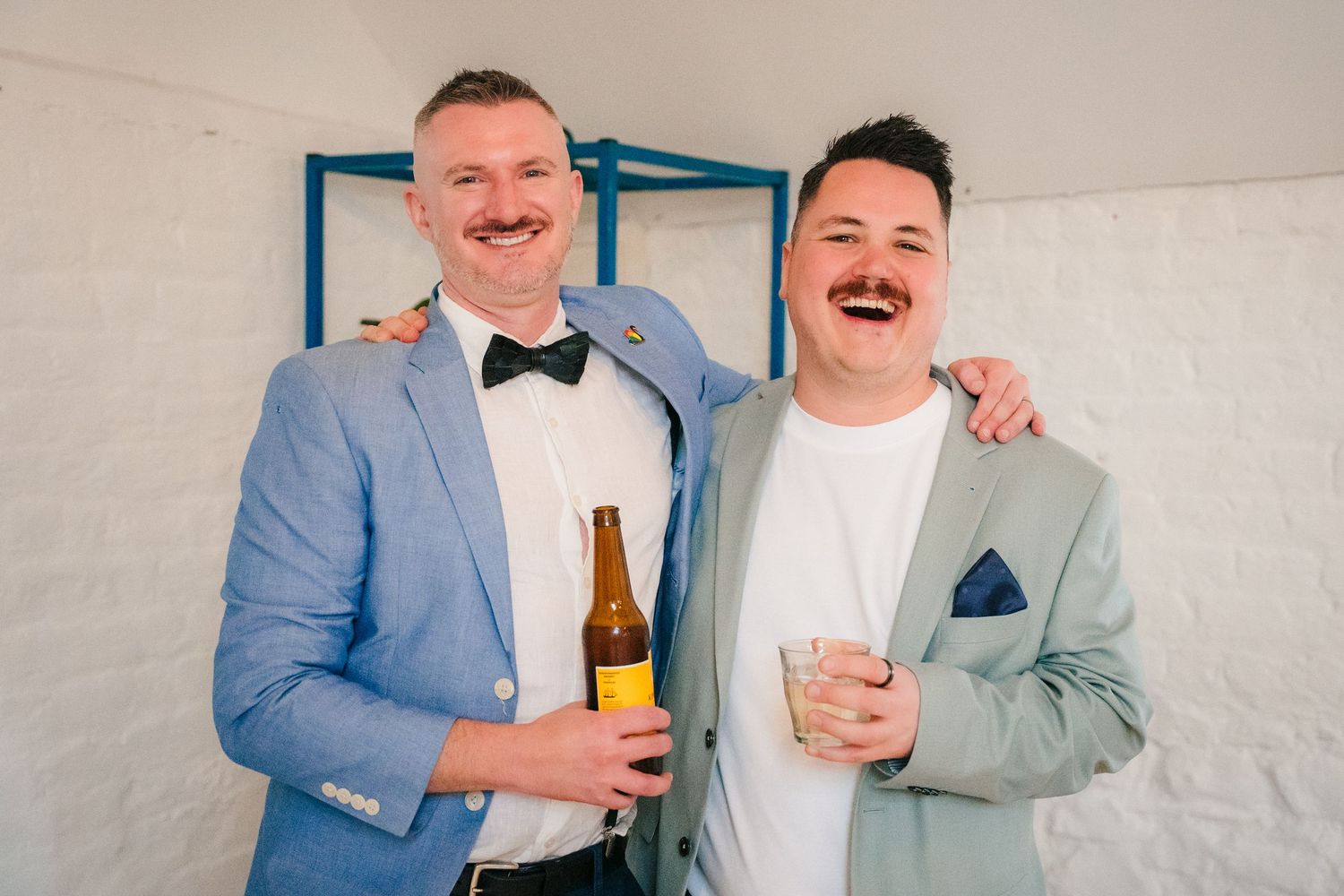 Wedding party members sharing drinks and laughter indoors. Same sex wedding PHOTOGRAPHER Dublin