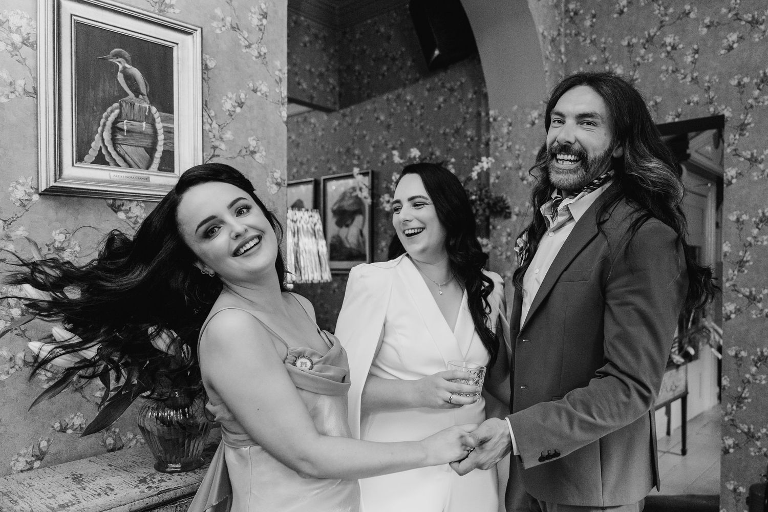 A black and white photo of three people sharing a candid laughing moment at an event. House Dublin Wedding Photographer