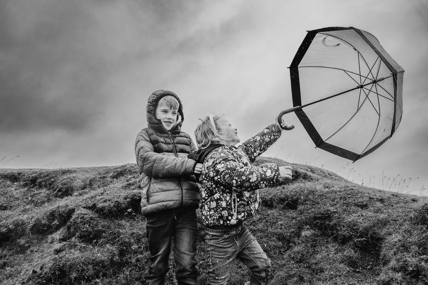 A collection of black and white photos showing people with umbrellas walking outdoors in moody weather Dublin Family photographer