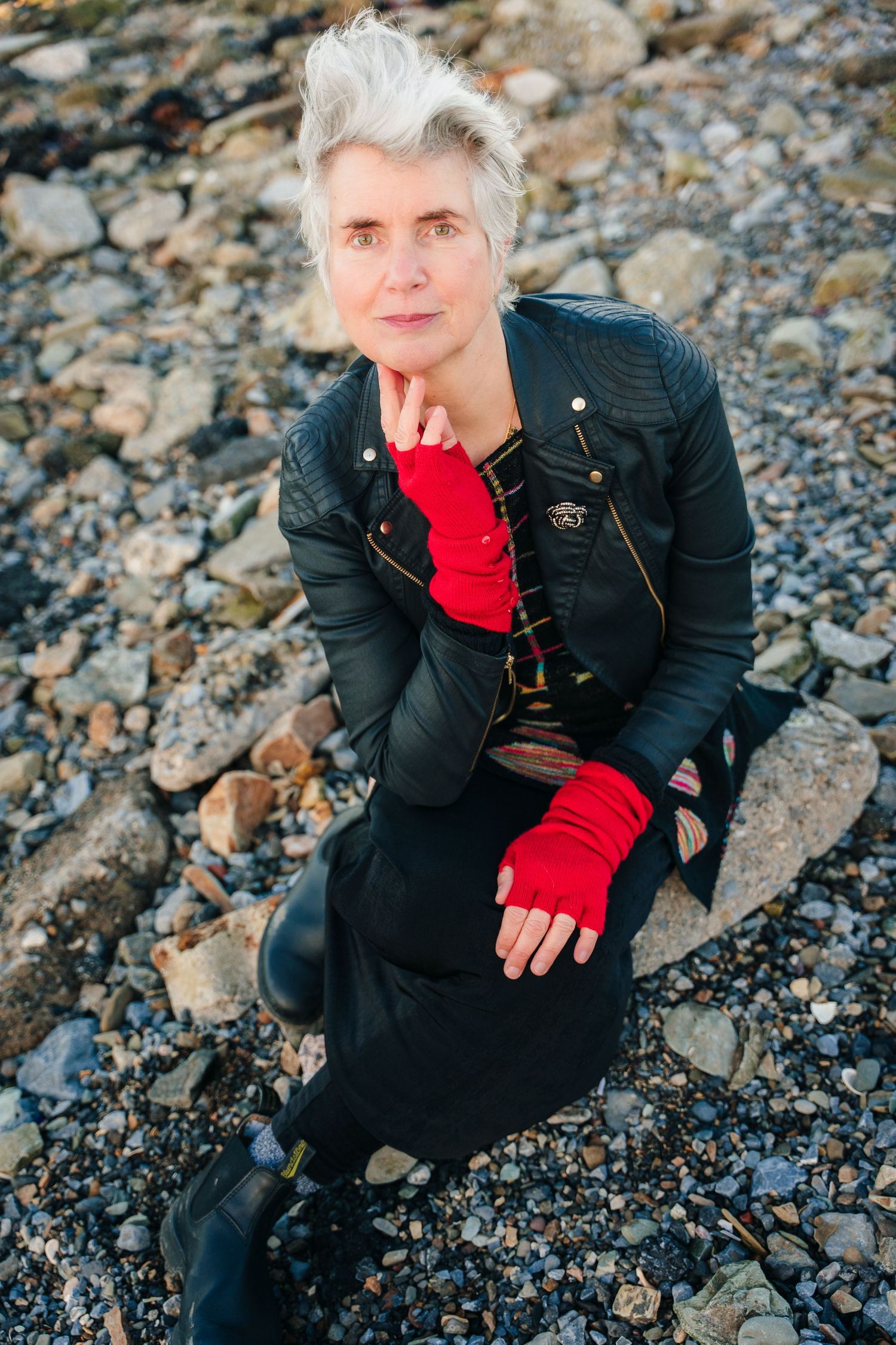 Artistic portraits on rocky ground showing someone in black with bright red fingerless gloves.  professional headshots branding photographer