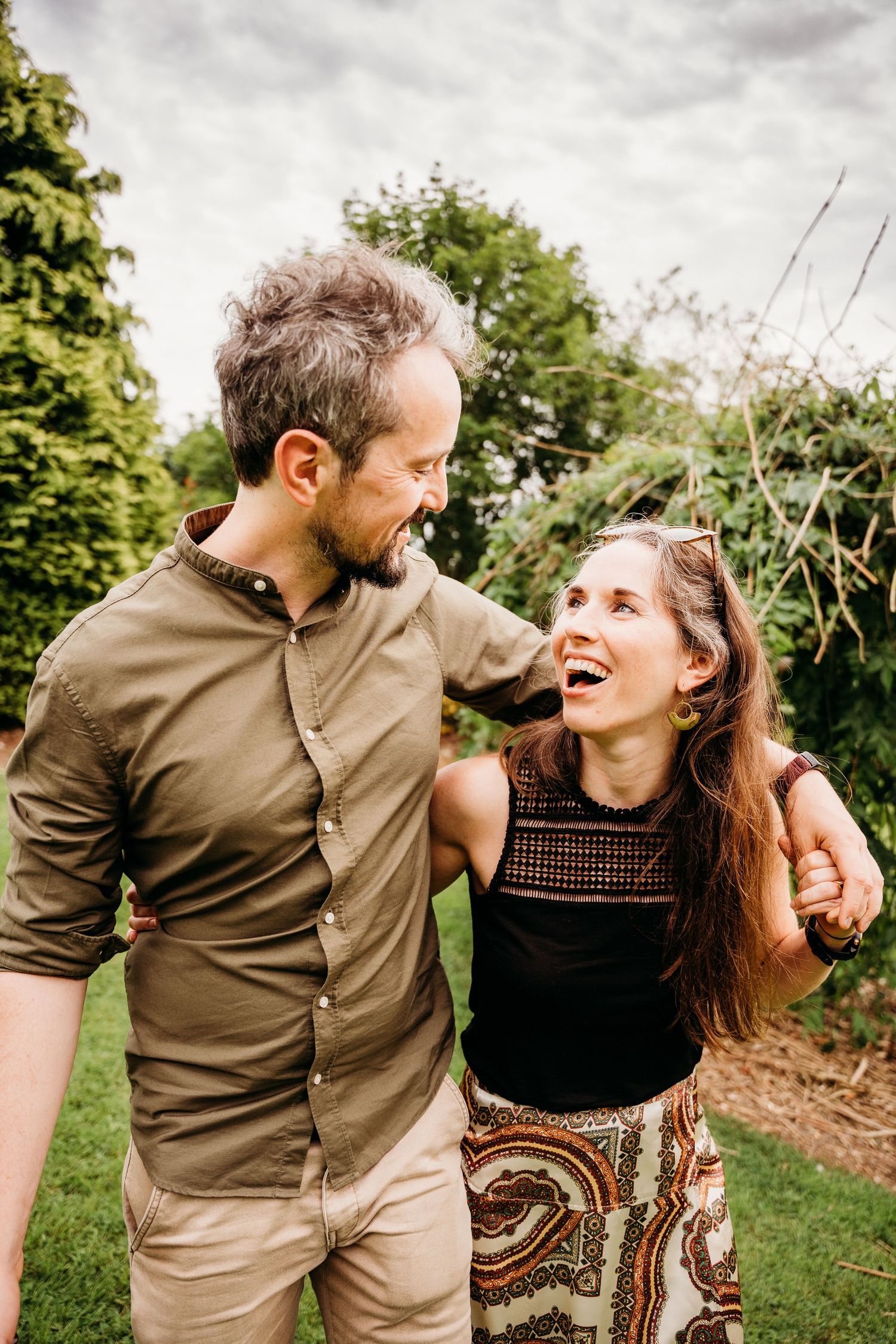A couple shares joyful laughter together while embracing outdoors in a natural setting during a photo session. PHOTOGRAPHER Dublin ireland
