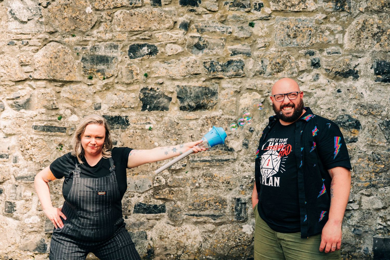 Two people stand and pose against a textured stone wall outside. PHOTOGRAPHER Dublin ireland