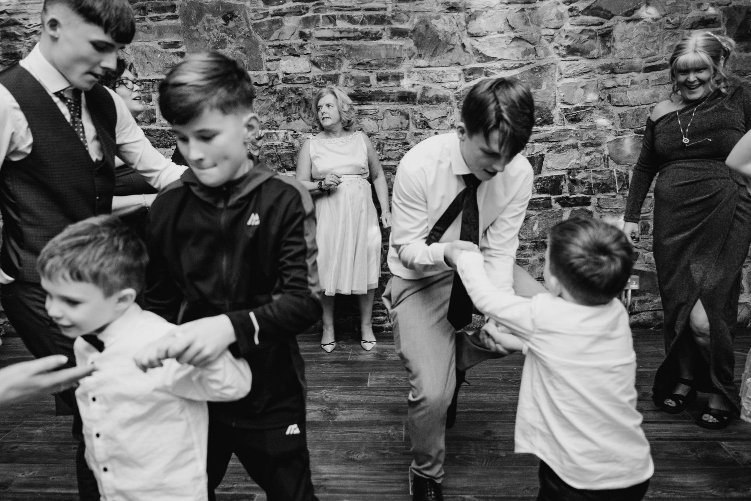 Black and white photo series showing intimate dance moments at a wedding celebration against a brick wall backdrop. Wedding photographer dub