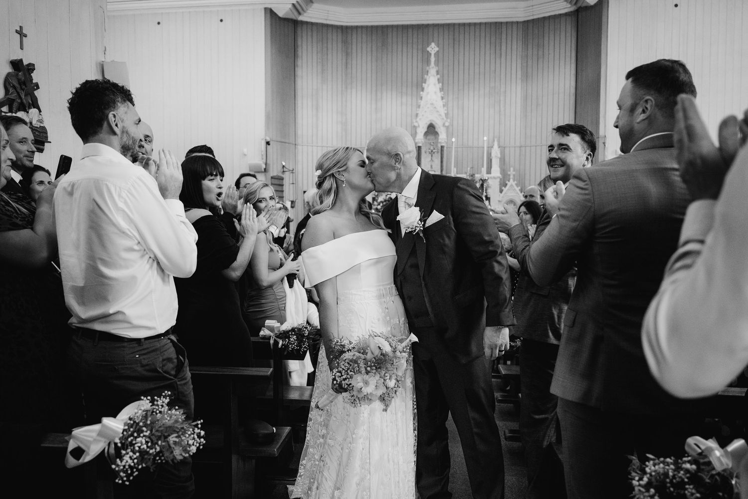Black and white photograph of guests celebrating during an indoor wedding reception. The Dean Dublin Wedding Photographer