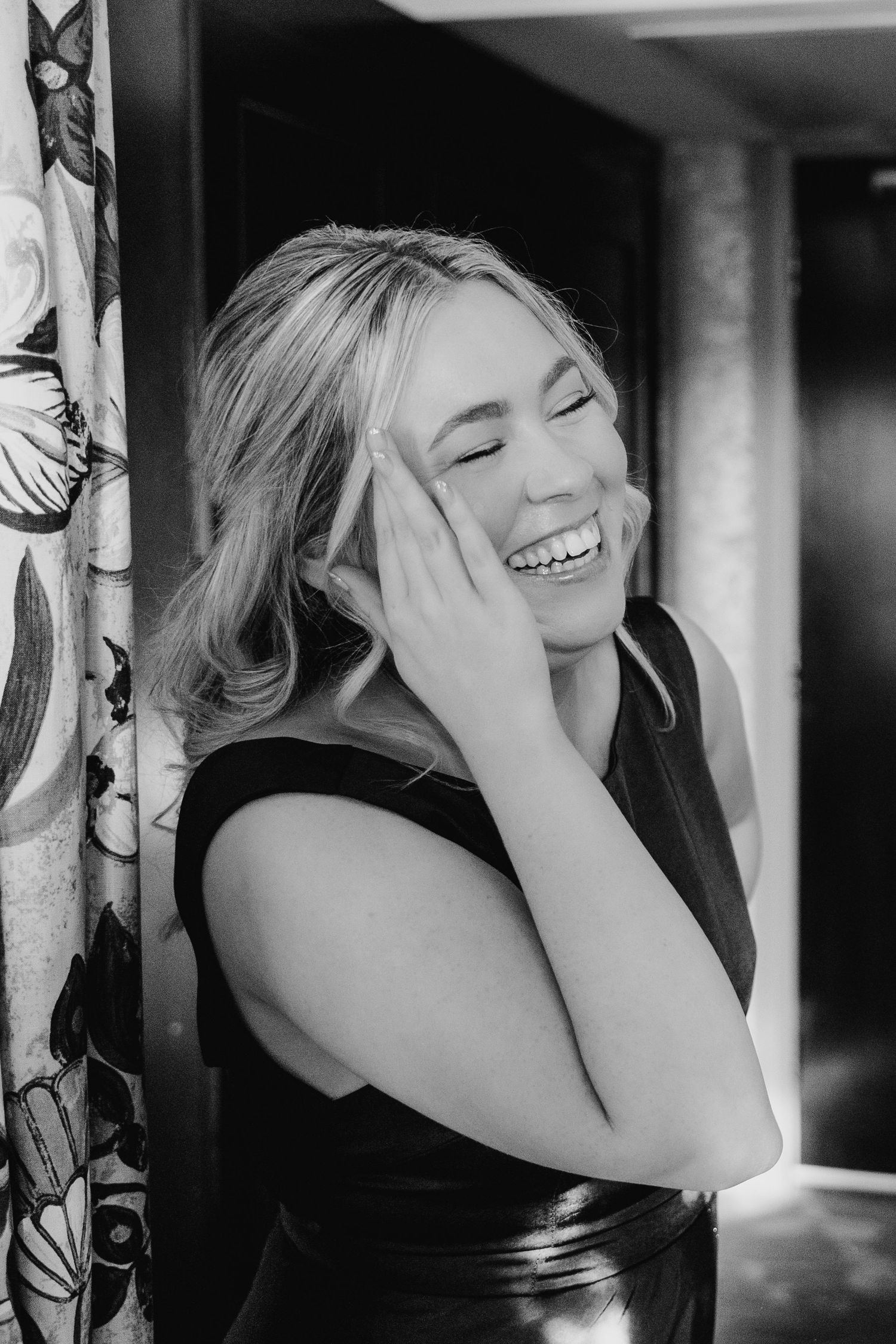 A joyful candid black and white portrait showing genuine laughter and emotion against a floral patterned background. City Hall Dublin Photog