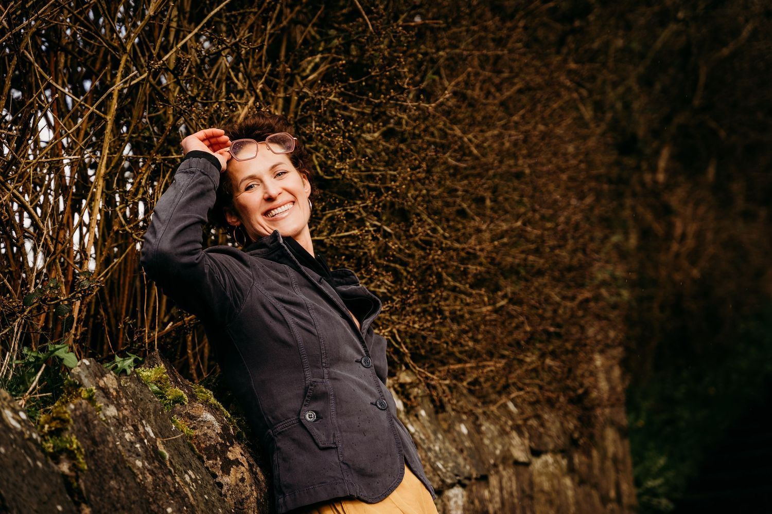 A person in a black jacket poses playfully against an autumn forest backdrop. Portrait PHOTOGRAPHER Dublin