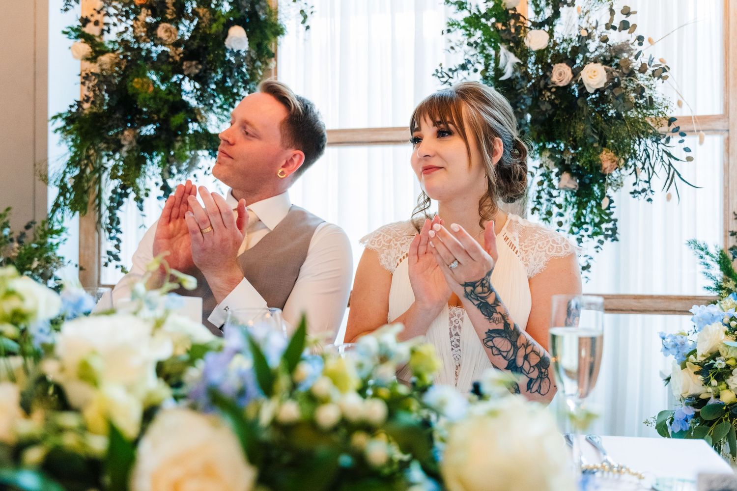Wedding celebration under floral arrangements with couples clapping during reception.PHOTOGRAPHER Dublin Ireland Wedding