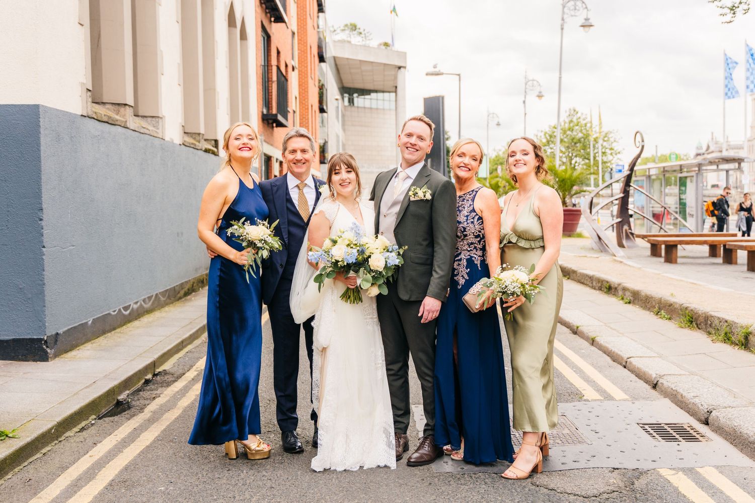 Wedding party poses for group photos on a quaint city street. PHOTOGRAPHER Dublin Ireland Wedding