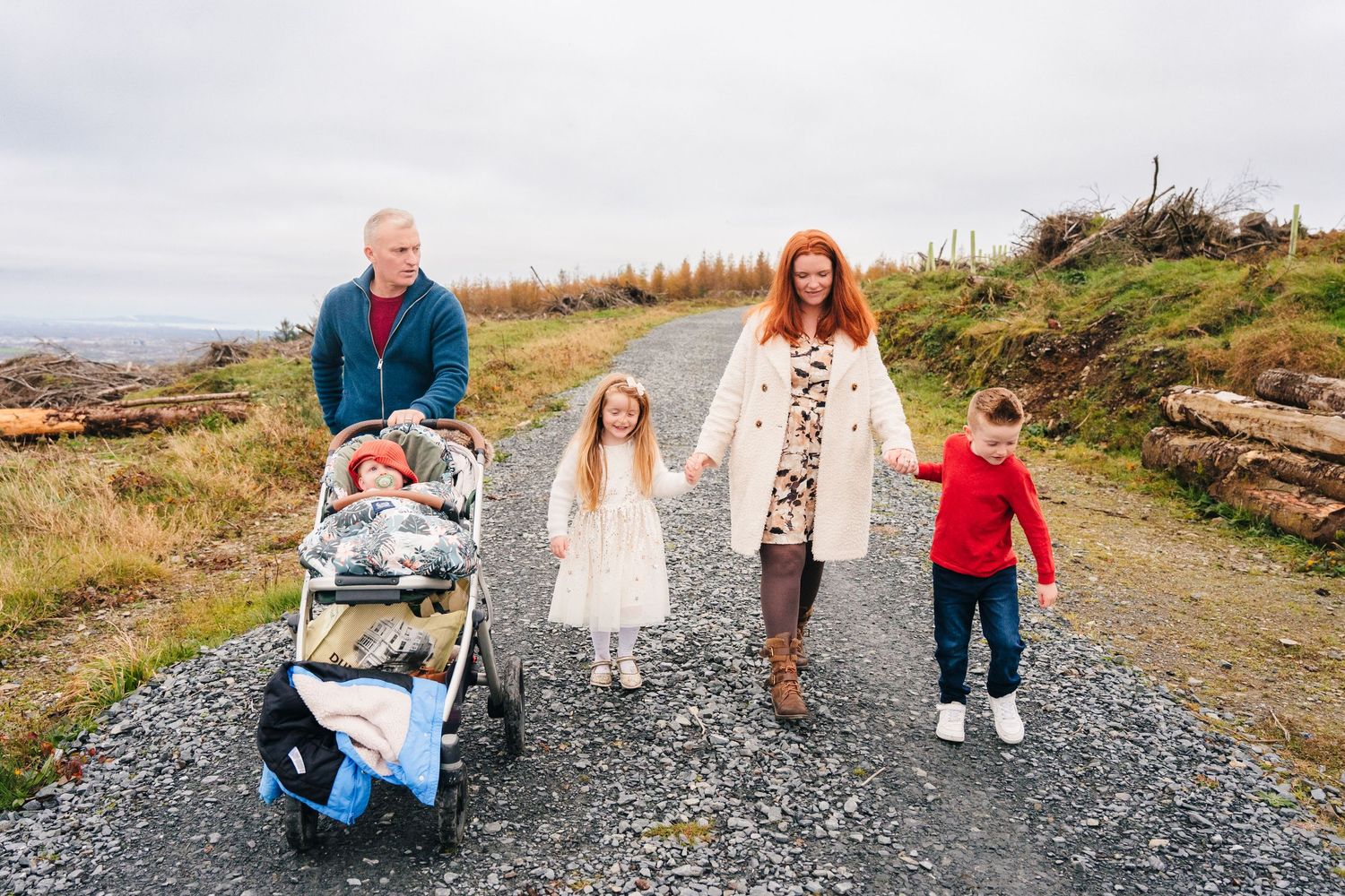 Family Photographer Dublin Ireland A family walking together on a mountain path with a stroller on a cloudy day.
