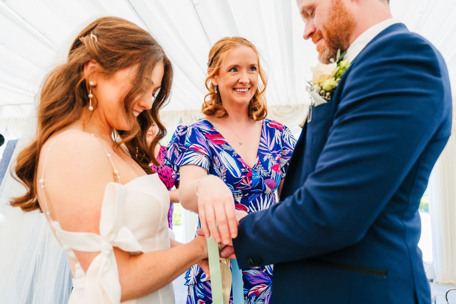 Castle Leslie Wedding Photographer Dublin Special moment during ring exchange ceremony inside white draped wedding venue.