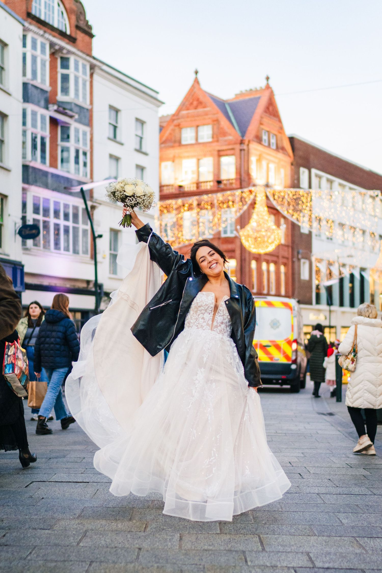 A person in a wedding dress twirls joyfully on a city street at dusk with historic buildings in the background. Wedding PHOTOGRAPHER Dublin
