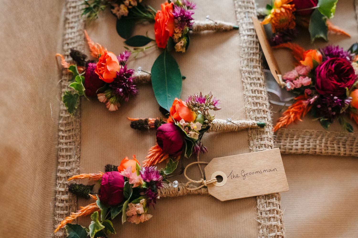 Vibrant floral arrangements with red and orange blooms laid out on burlap and book pages. Wedding Photography Trim Castle Ireland