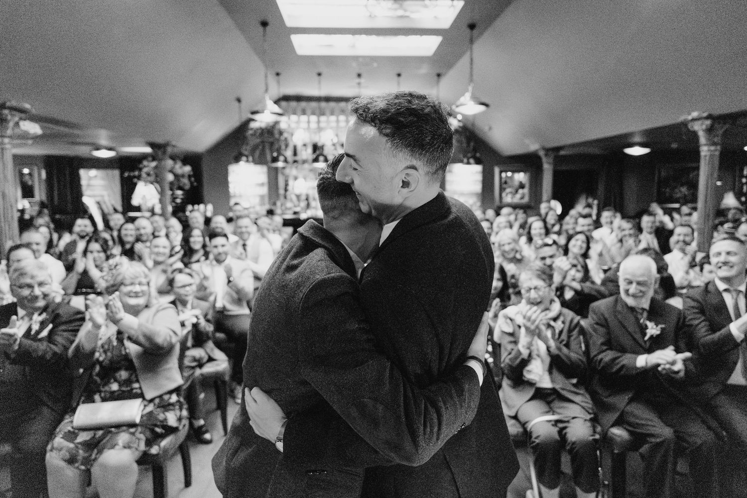 Large crowd gathered in a dimly lit venue during a celebration. Marco Pierre Dublin Wedding Photographer