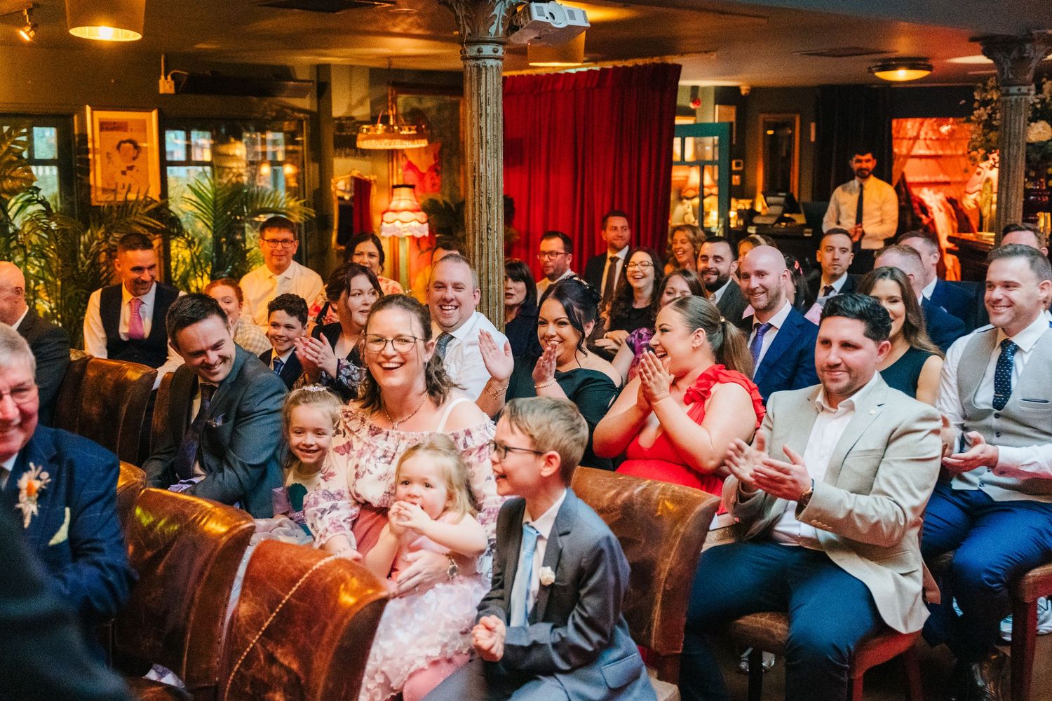 Wedding reception guests enjoying themselves in a dimly lit venue with warm ambient lighting. Marco Pierre Dublin Wedding Photographer