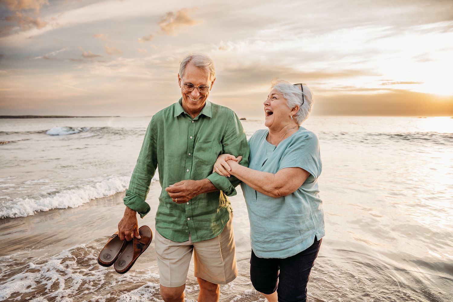 Couple enjoying a romantic sunset walk along the beach with waves crashing on the shore. Family PHOTOGRAPHER Dublin