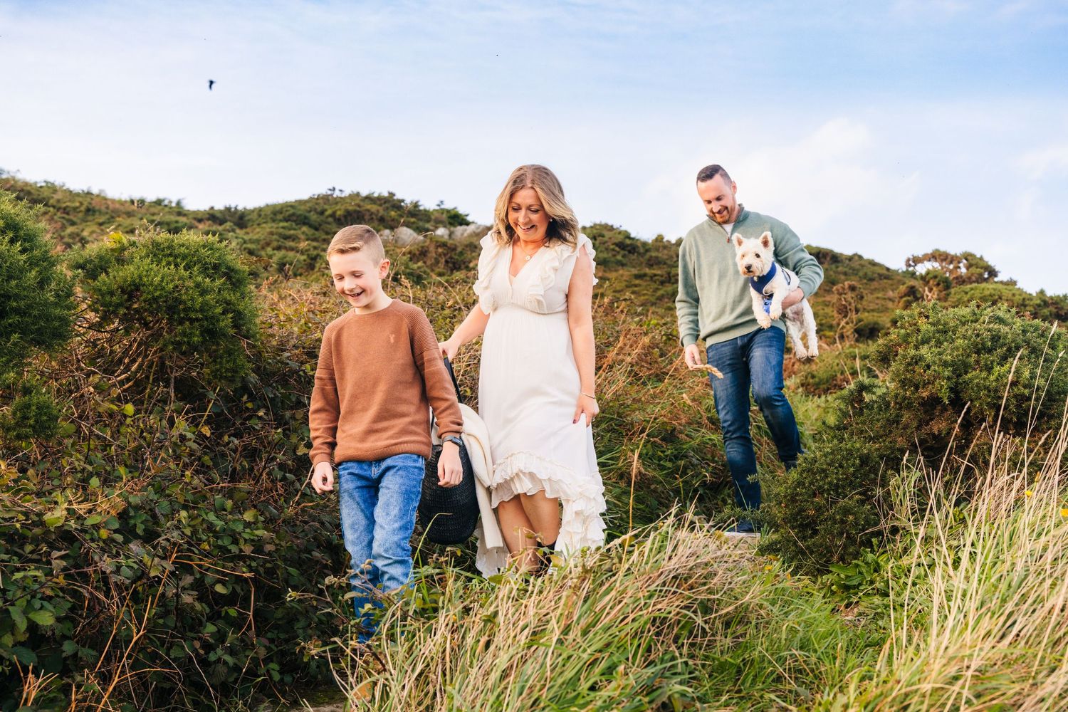 Group walking together through scenic hillside meadow surrounded by lush vegetation on sunny summer day. Photographer dublin ireland