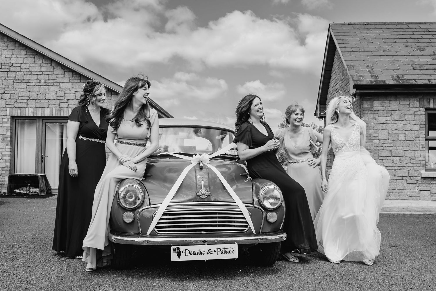 Classic vintage wedding cars parked in front of brick buildings on a sunny day with puffy white clouds. Wedding PHOTOGRAPHER Dublin