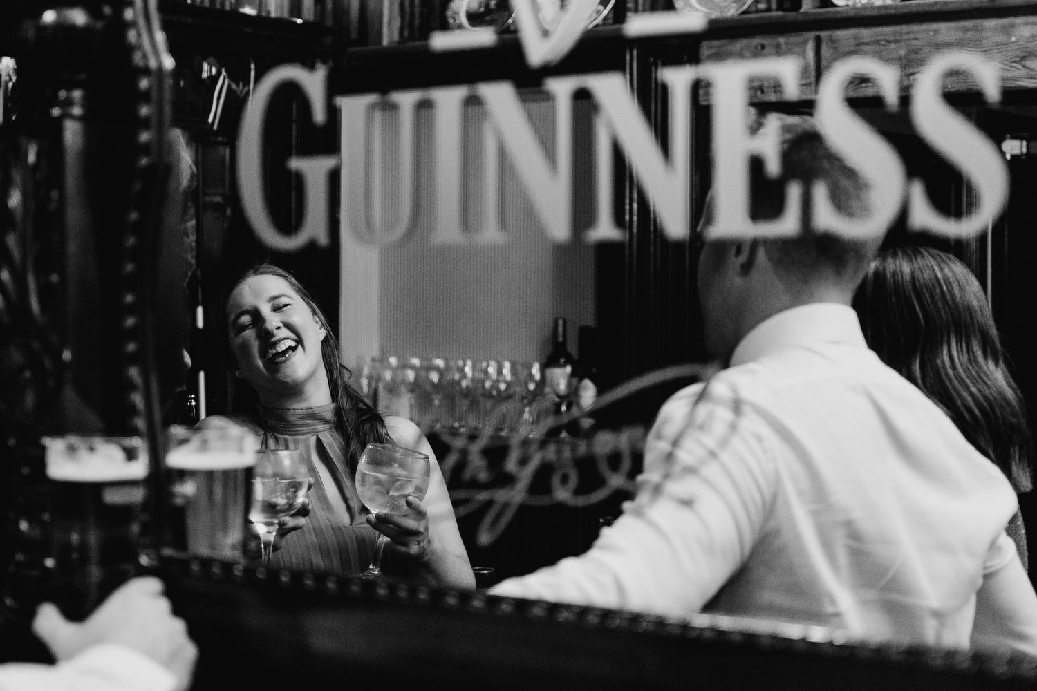 A candid black and white moment of laughter at a Guinness bar. Wedding PHOTOGRAPHER Dublin