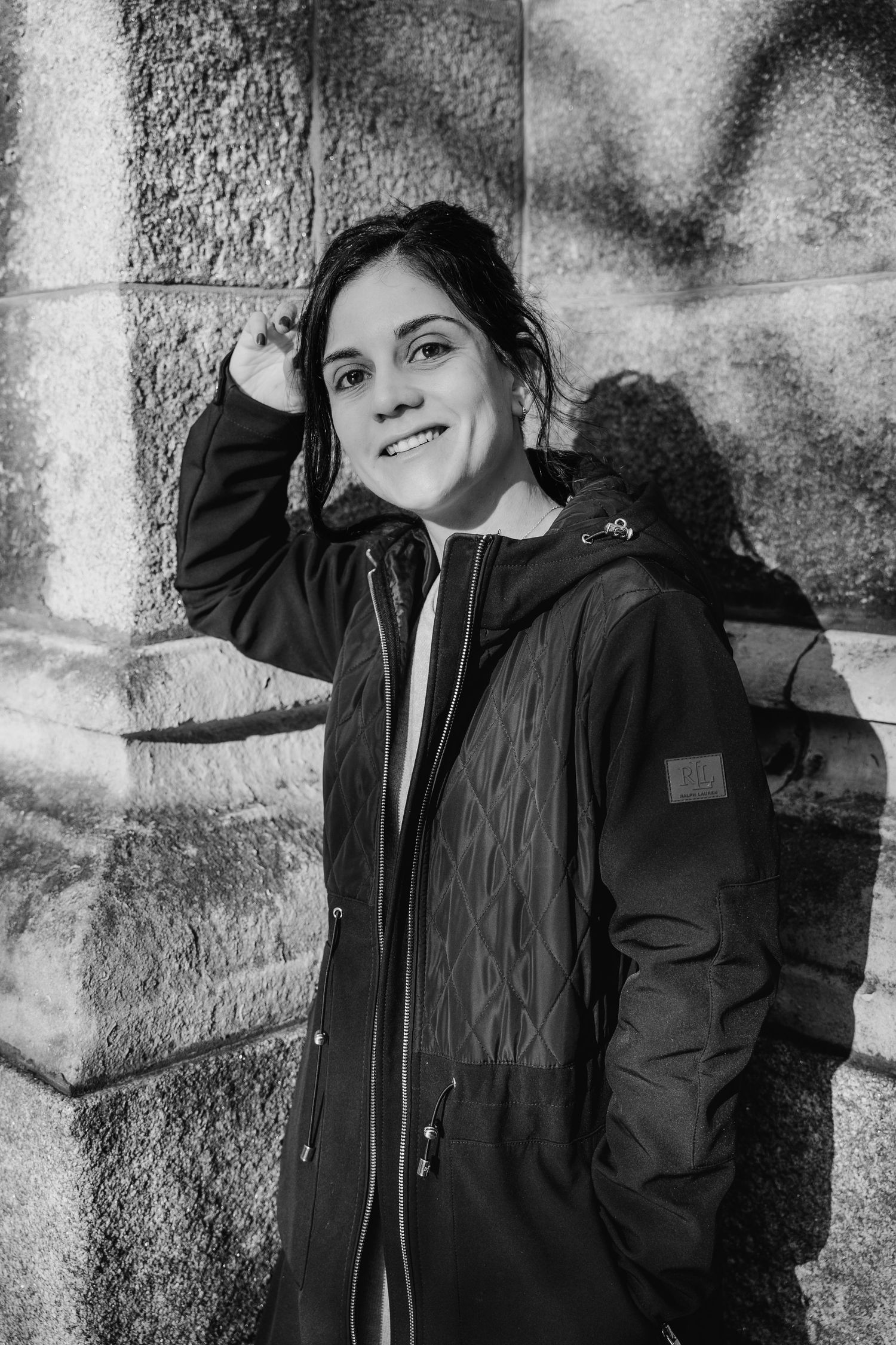 A series of black and white portraits showing someone in a dark winter coat posing against a textured stone wall. professional headshots dub