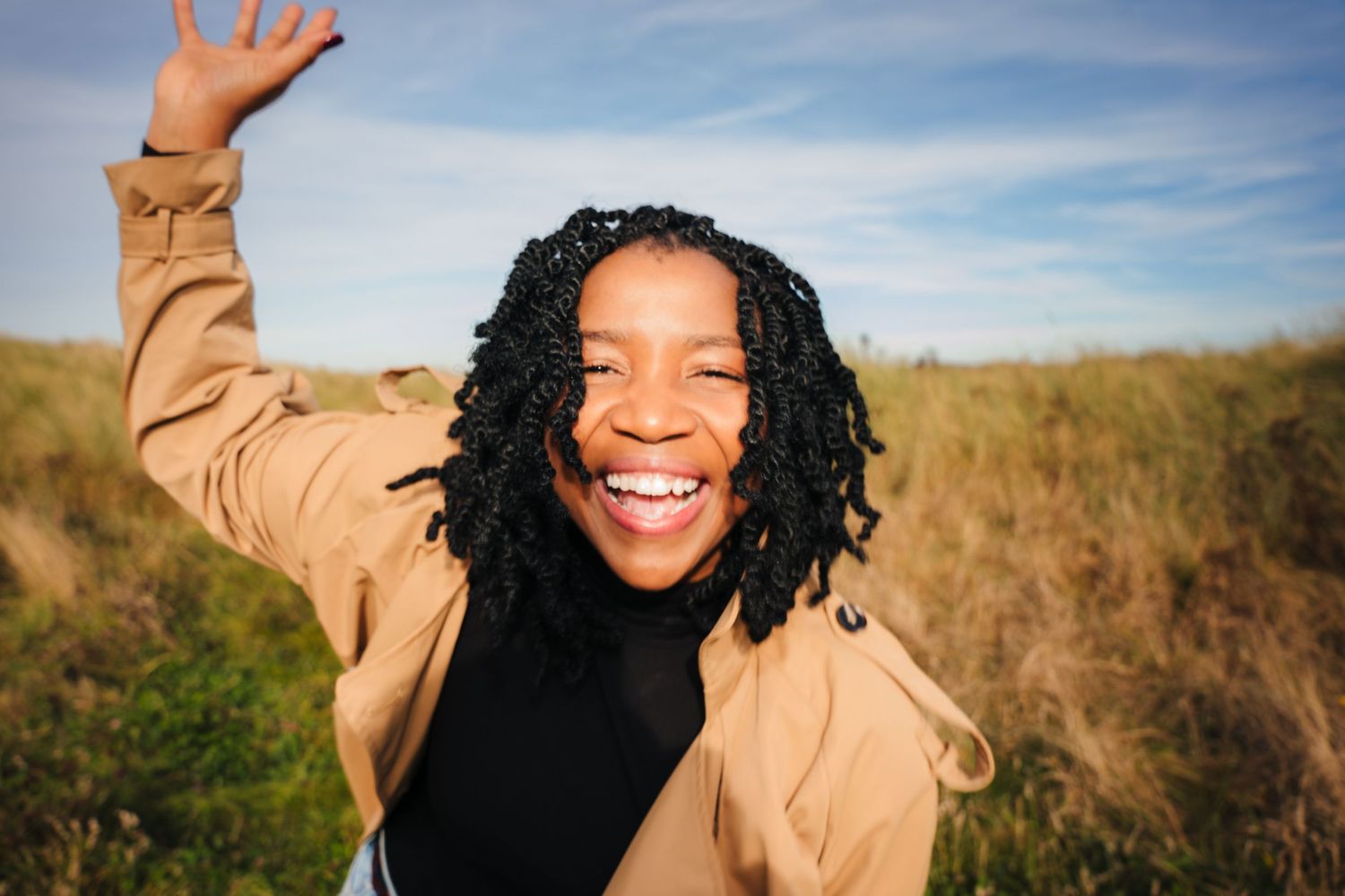 Person in beige coat gestures playfully outdoors on sunny day. Dublin professional headshots photographer