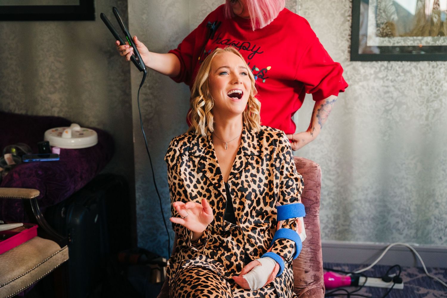 A person wearing a leopard print dress and red jacket laughs joyfully while getting ready. Wedding photographer dublin