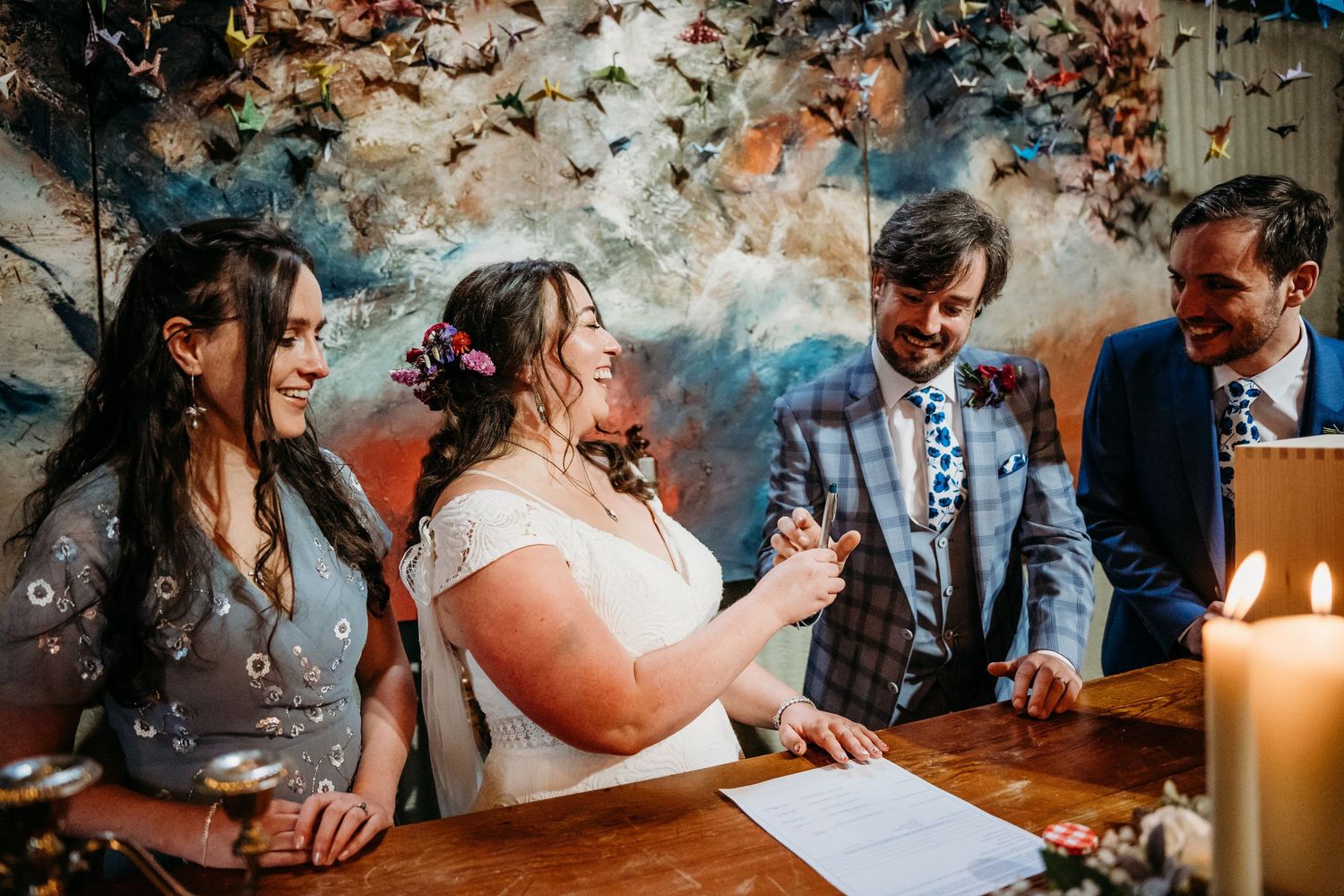 Wedding guests laughing and celebrating around a candlelit table at reception. Wedding photographer Dublin