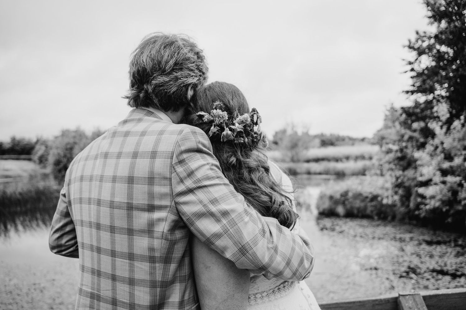A romantic black and white photo of newlyweds embracing under an umbrella in the rain. Wedding photographer Dublin