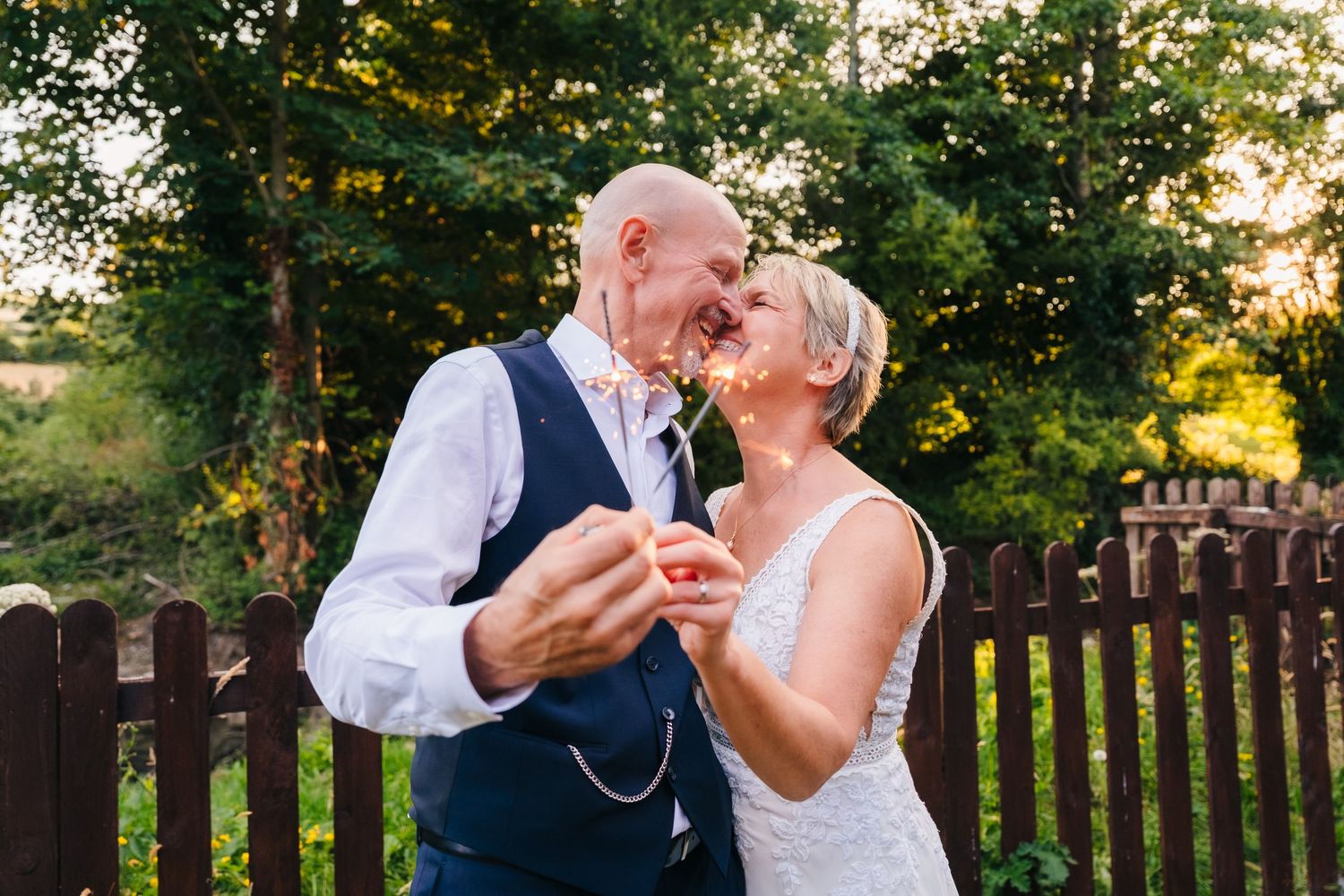 Wedding photographer Dublin Bride and groom sharing a romantic moment, touching noses and smiling outdoors near a wooden fence.
