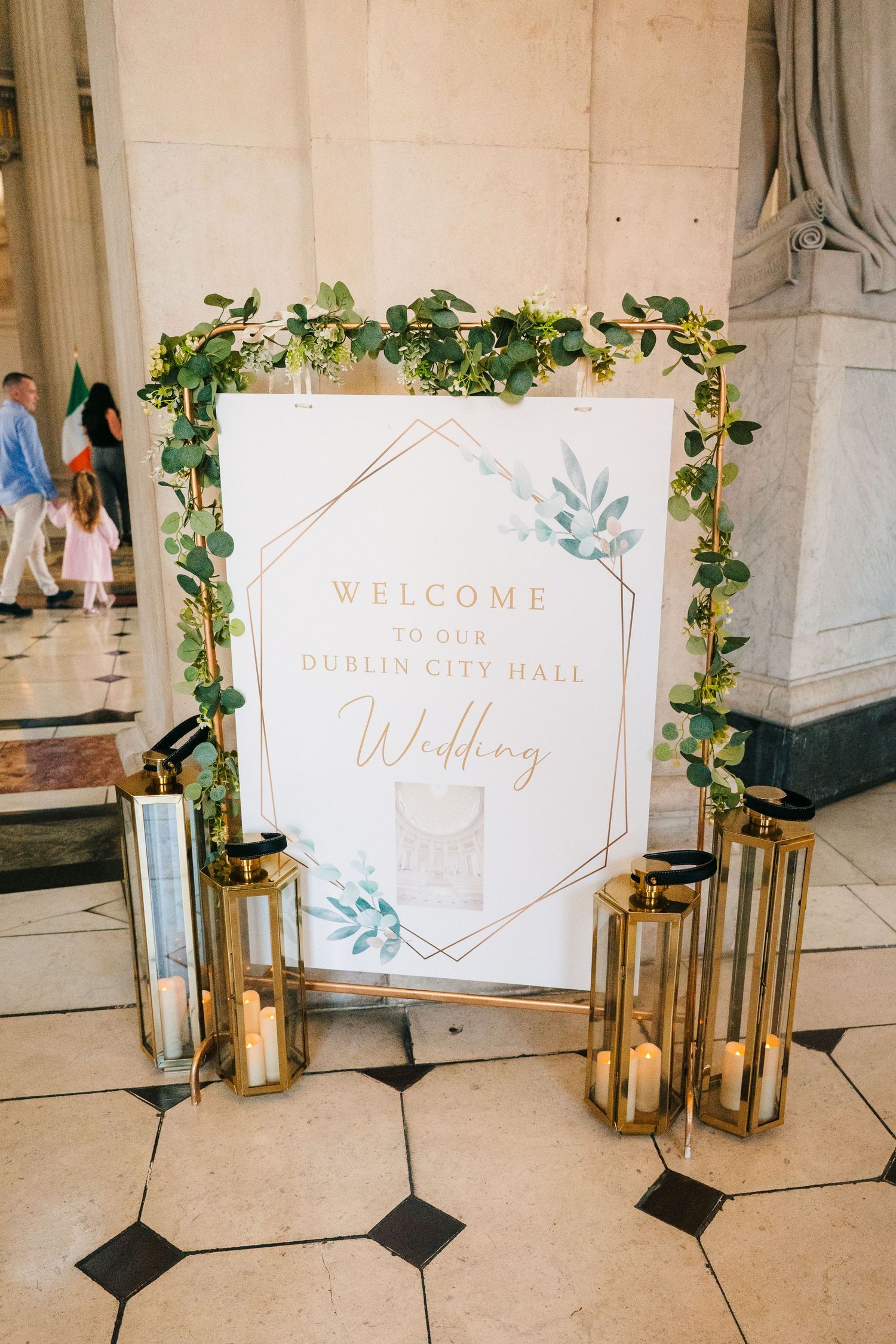 Wedding welcome signs with gold geometric frames and lanterns displayed on marble floor. v