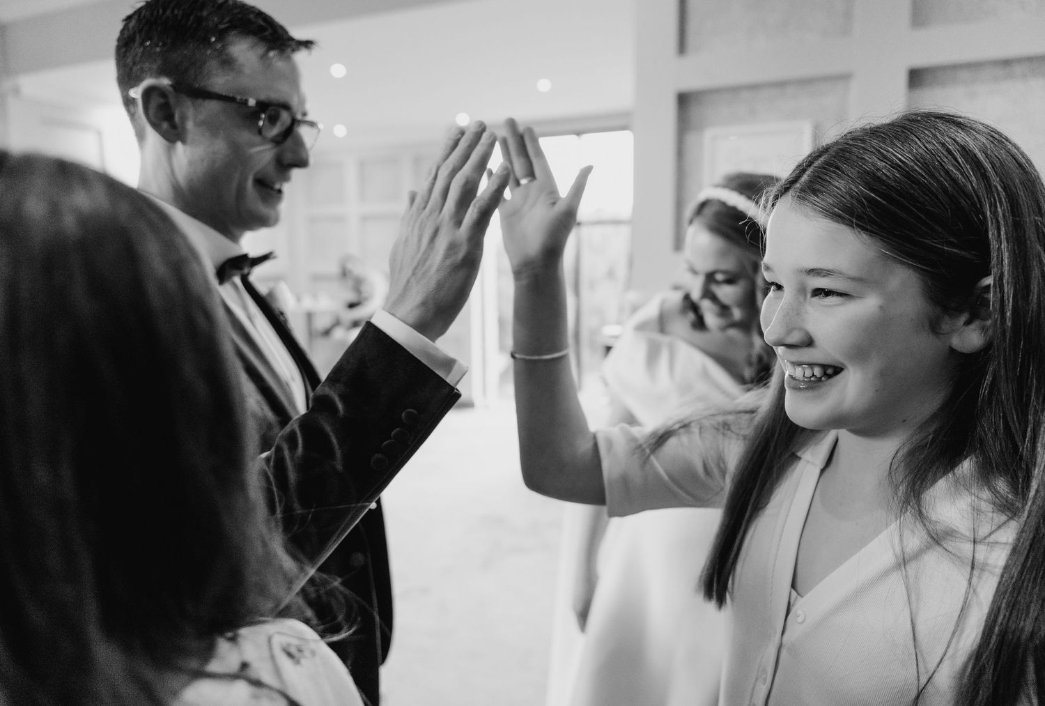Wedding guests celebrate with high fives and joyful expressions at an indoor reception.  Wedding PHOTOGRAPHER Trim Castle