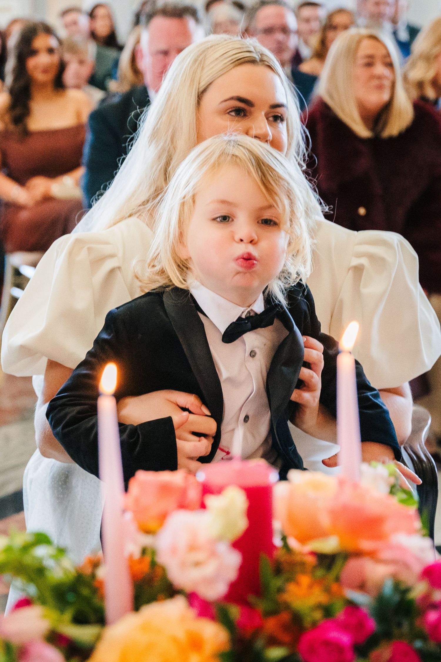 Wedding guests gather around a table with pink floral centerpieces and lit candles during a celebration. City Hall Dublin Photographer