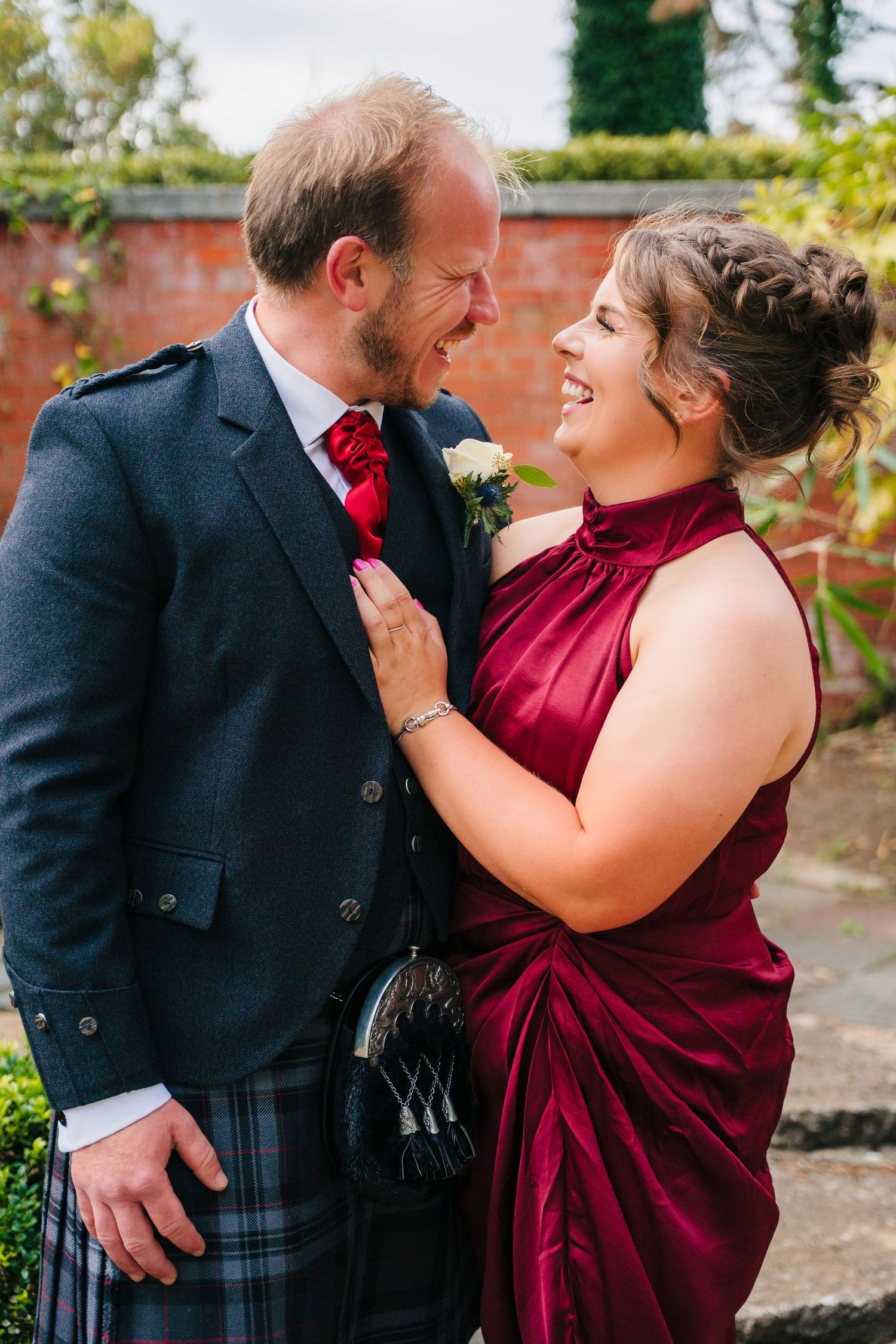 Couple in traditional Scottish wedding attire share intimate moments in a garden setting. Portmarnock Hotel Wedding PHOTOGRAPHER Dublin