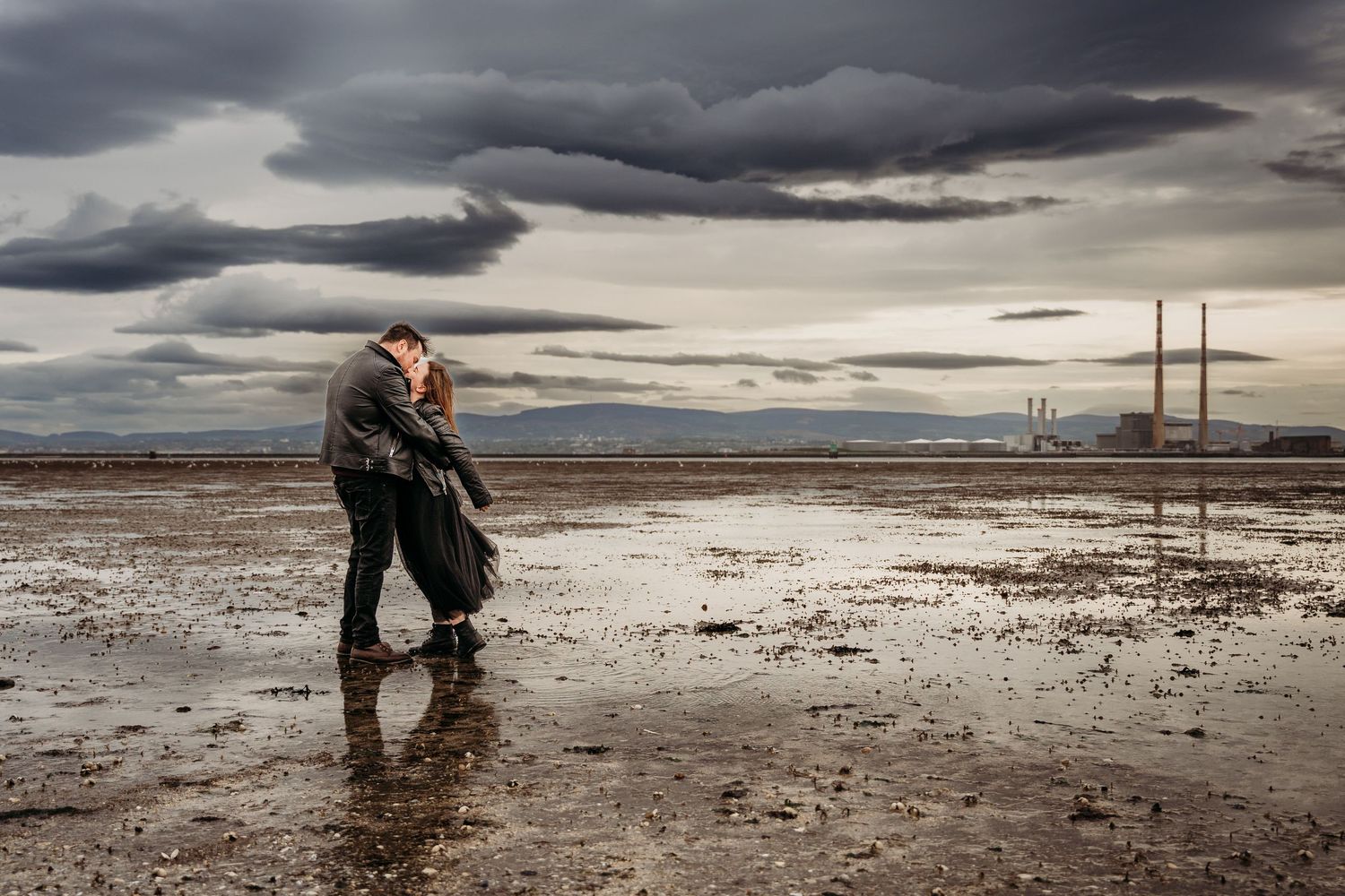 Dramatic landscape of wet beach at low tide with stormy clouds overhead. engagement PHOTOGRAPHER Dublin