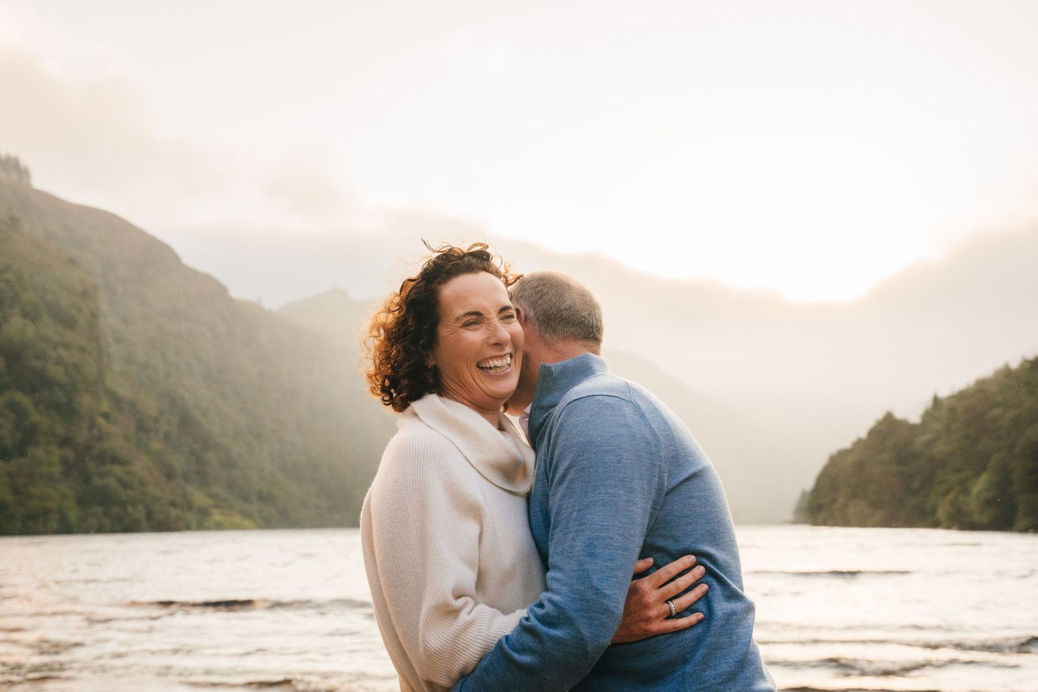 Family photographer Ireland Dublin Intimate lakeside embrace with mountains and sunset in the background.