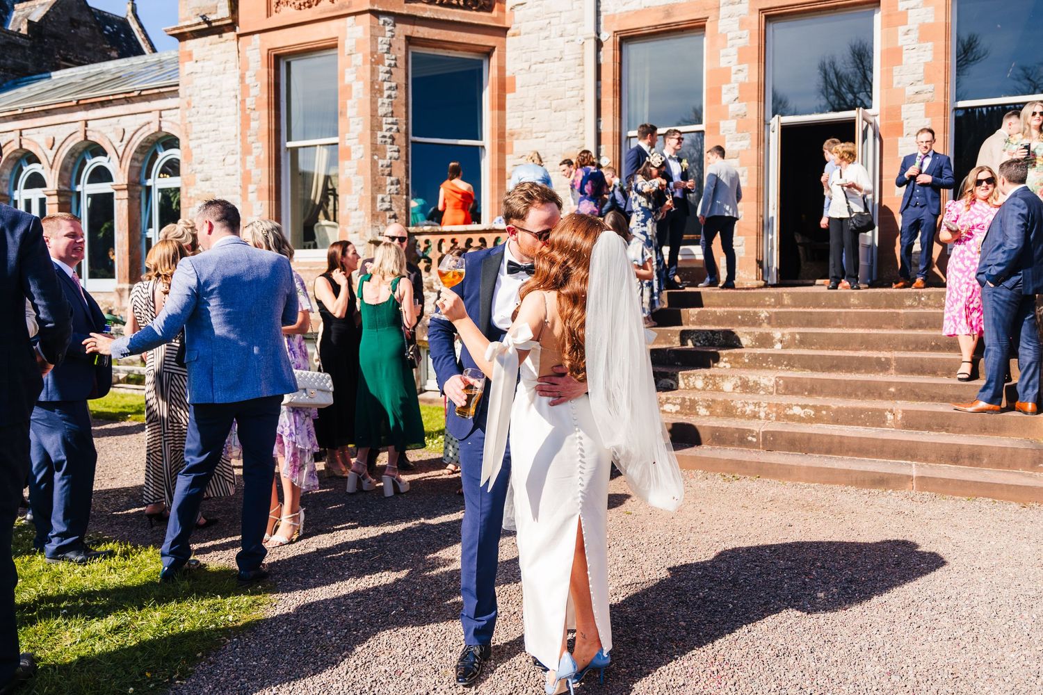 Castle Leslie Wedding Photographer Dublin Wedding celebration with guests gathered outside a beautiful sandstone building.