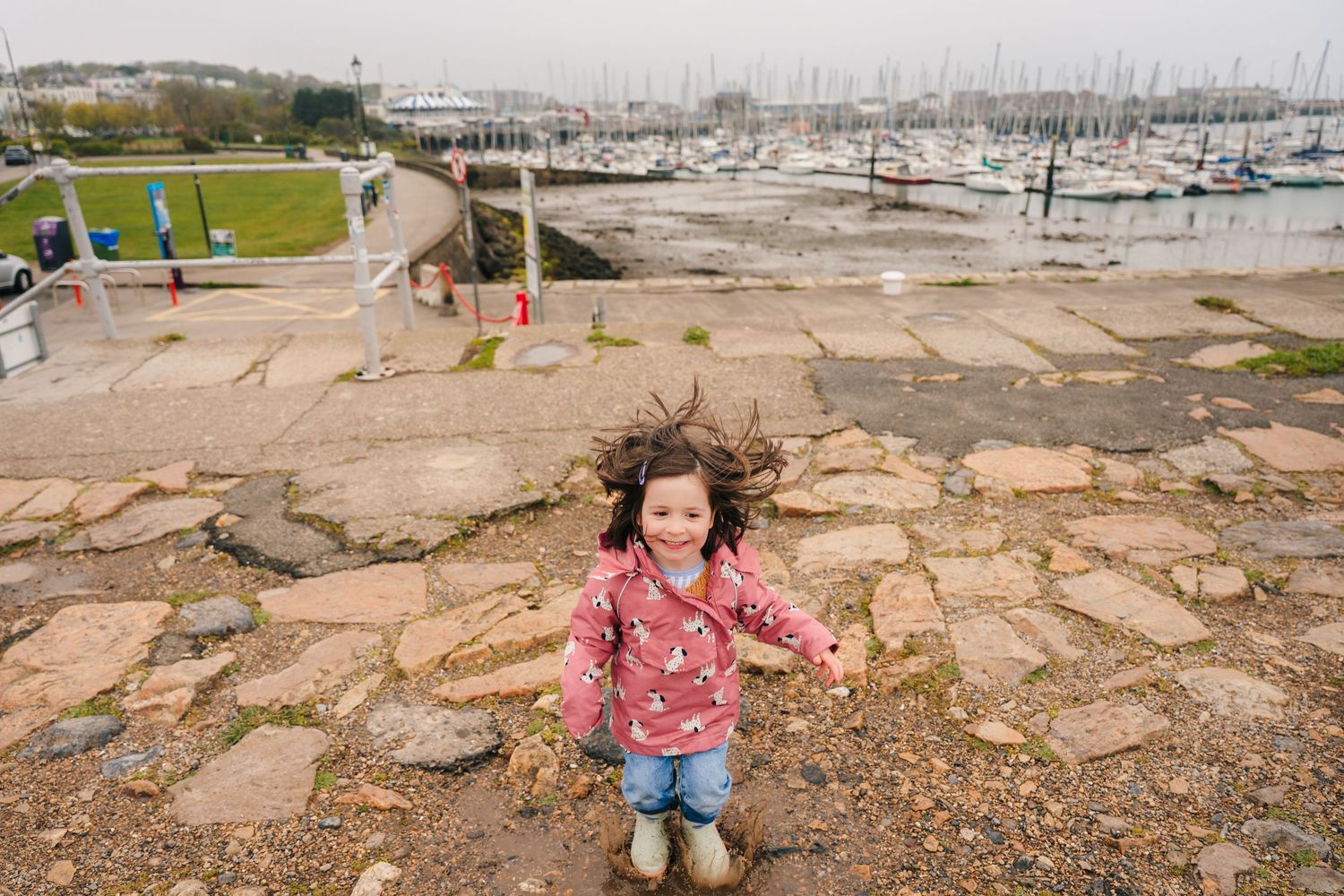 Children explore rocky coastline at low tide near marina with boats in background. PHOTOGRAPHER Dublin