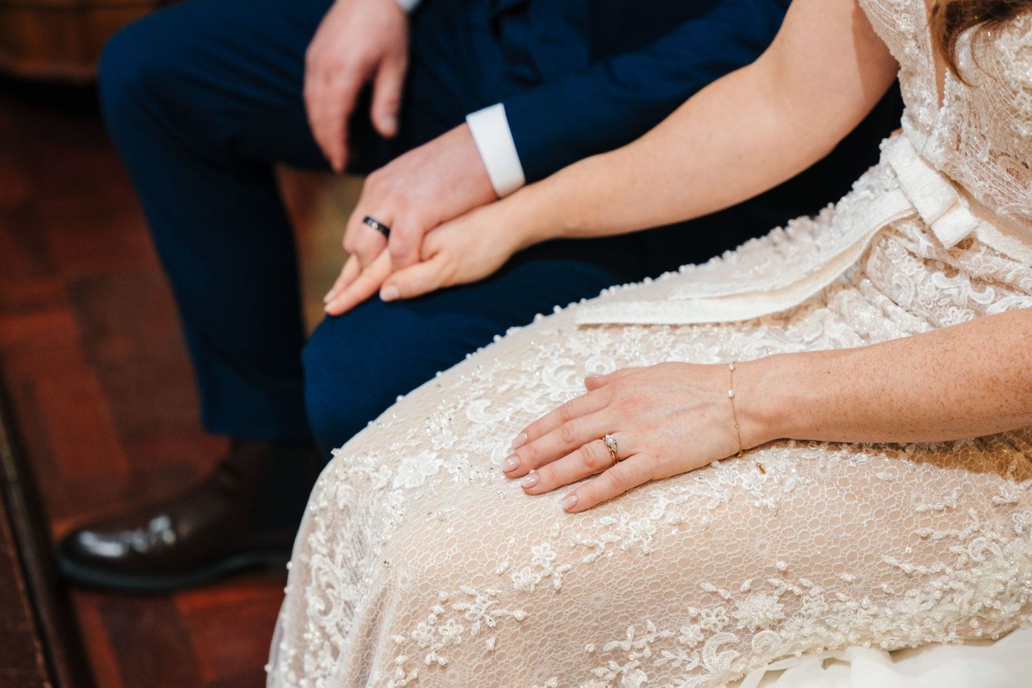 Detail shots of intricate beadwork and lace on wedding dress during ceremony.