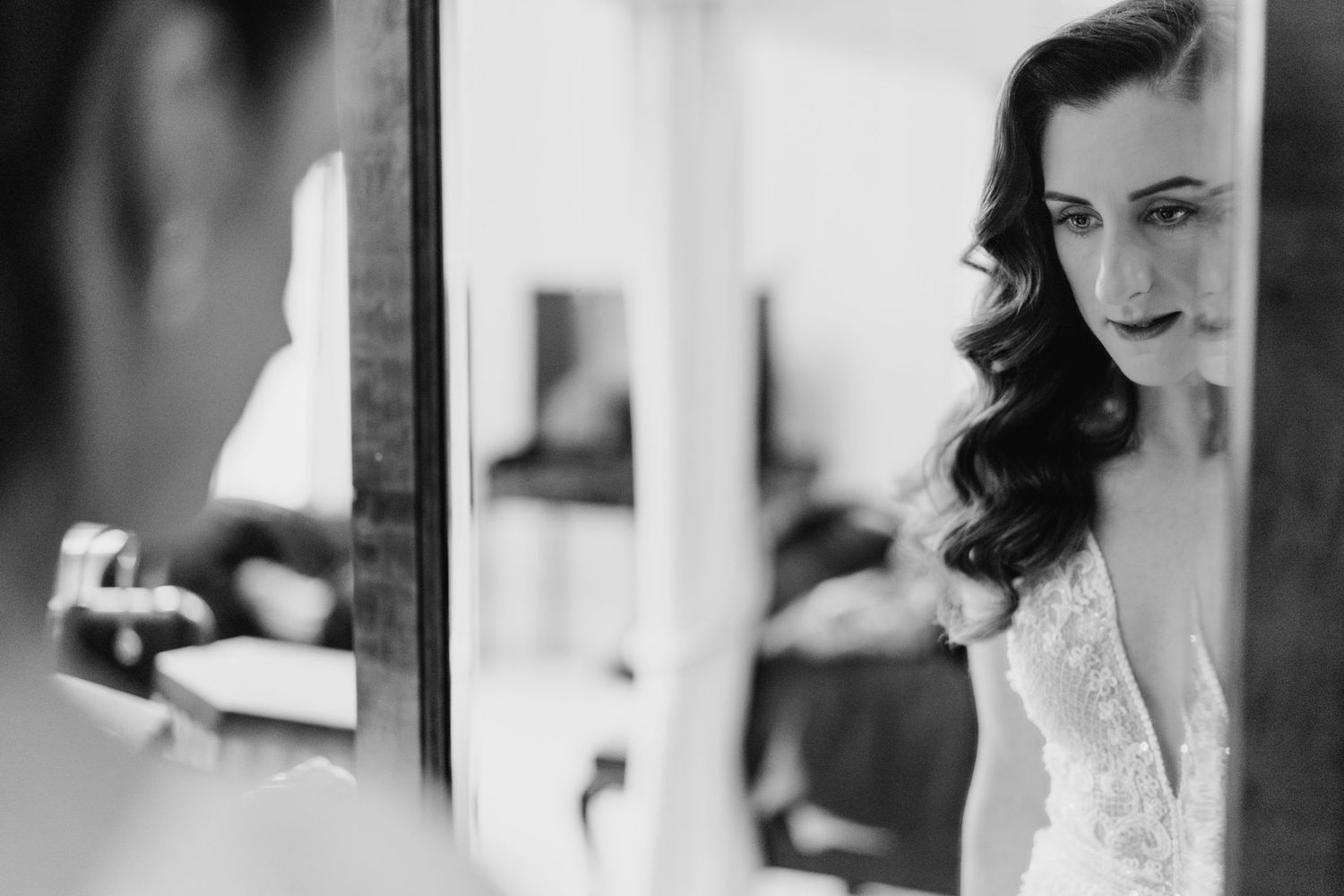 Bride getting ready in a black and white photo series showing makeup application and styling.
