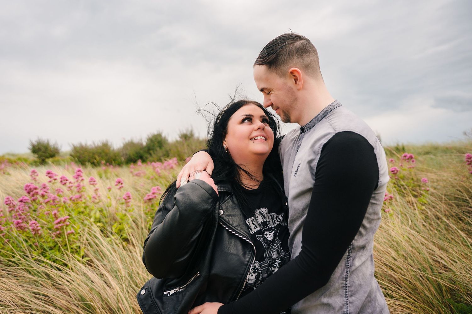 Couple sharing an intimate moment among pink wildflowers and tall grass on an overcast day. PHOTOGRAPHER Dublin ireland