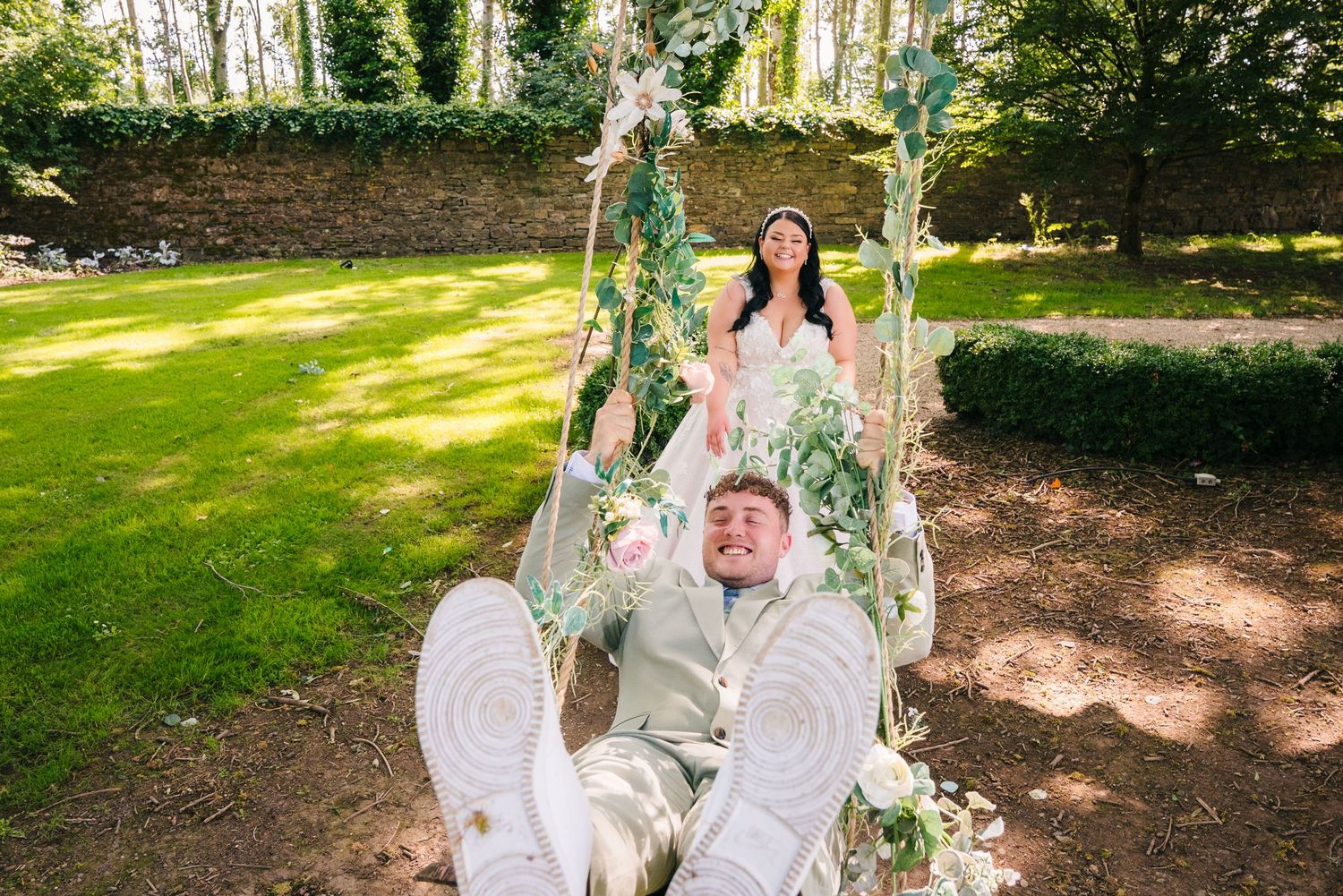Couple on an ornate white swing in a sunny garden setting during their wedding celebration. Wedding PHOTOGRAPHER Dublin