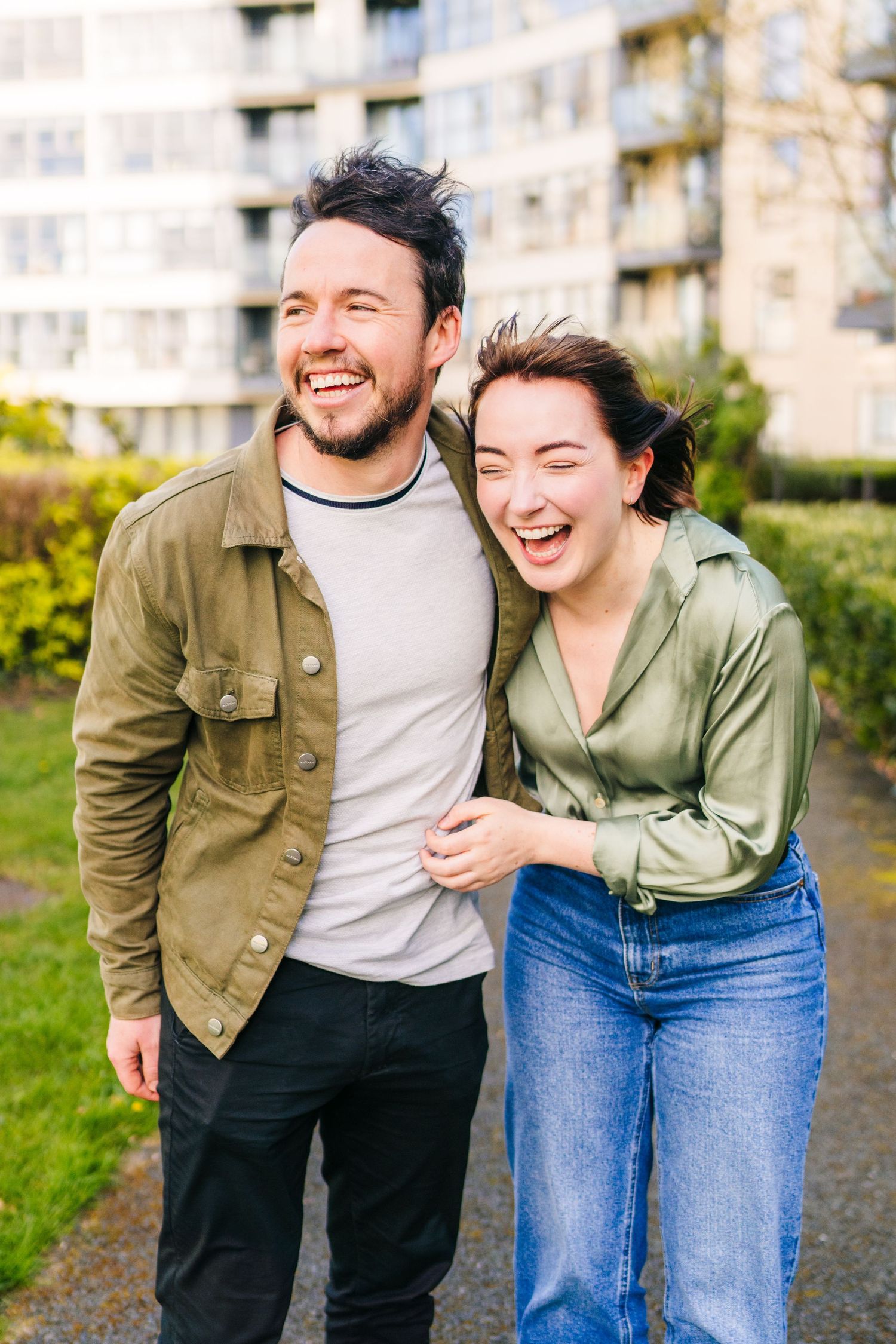 Happy couple laughing together outdoors in front of apartment building wearing casual jackets. PHOTOGRAPHER Dublin ireland