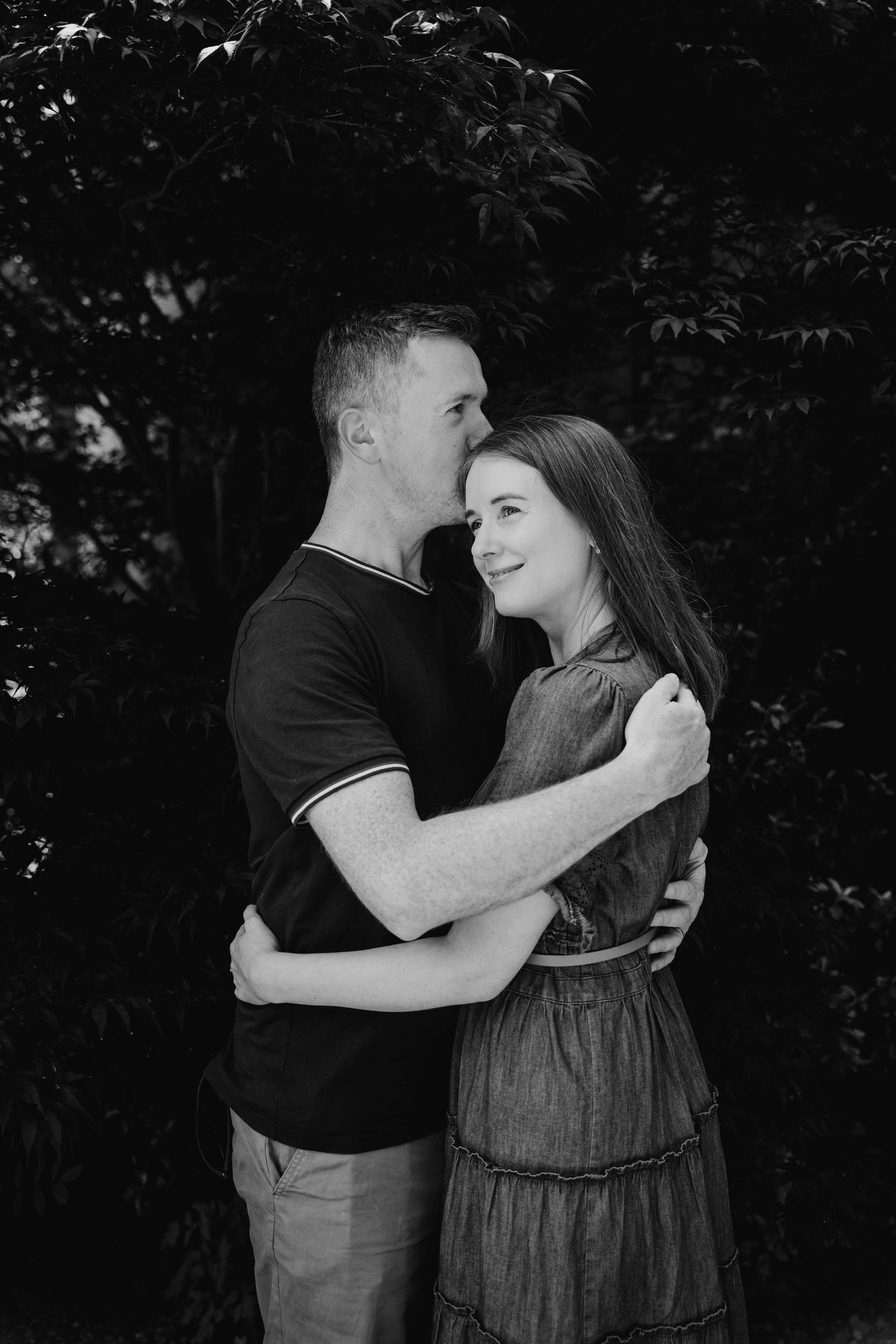 Black and white engagement photos show a romantic couple embracing outdoors in a natural setting. PHOTOGRAPHER Dublin ireland