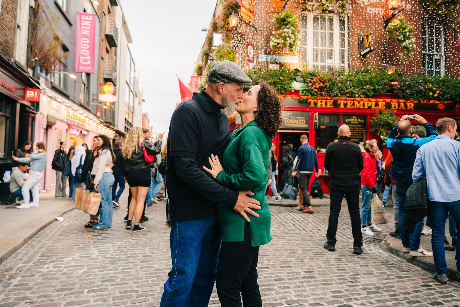 Bustling cobblestone street in Edinburgh's historic Royal Mile with tourists walking past colorful storefronts and shops. PHOTOGRAPHER Dubli