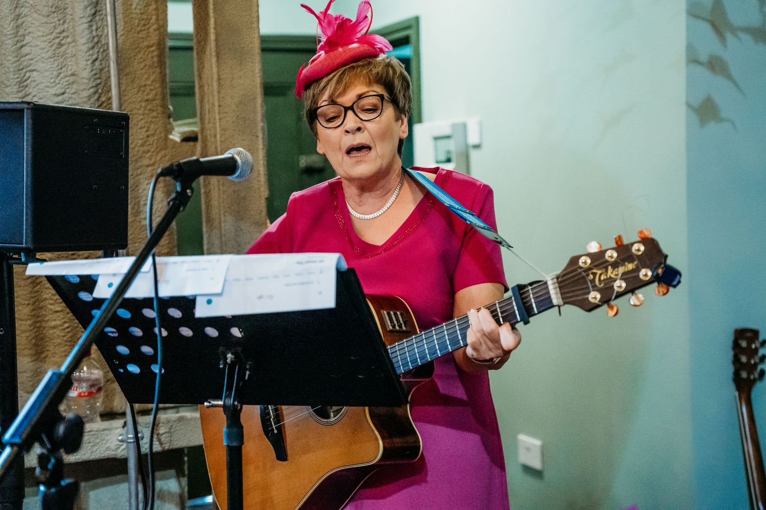 Musicians perform with acoustic guitars at a wedding celebration with pink decor accents. Wedding photographer Dublin