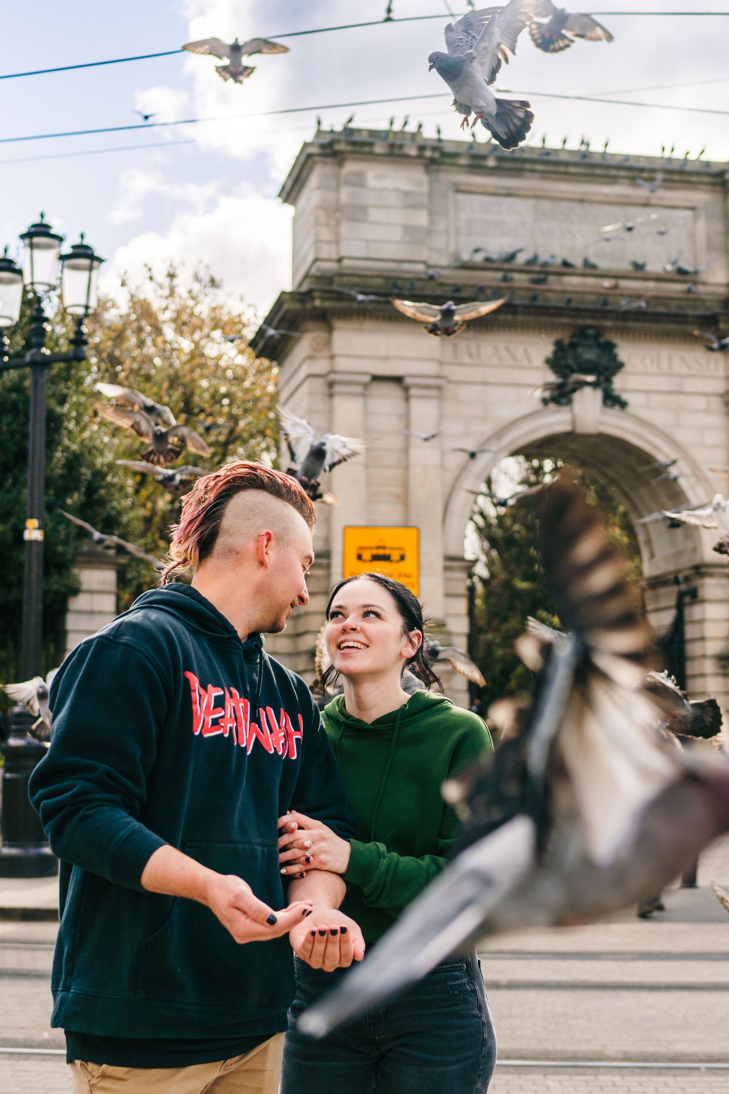 People interacting near architectural monument with pigeons flying overhead. PHOTOGRAPHER Dublin Ireland