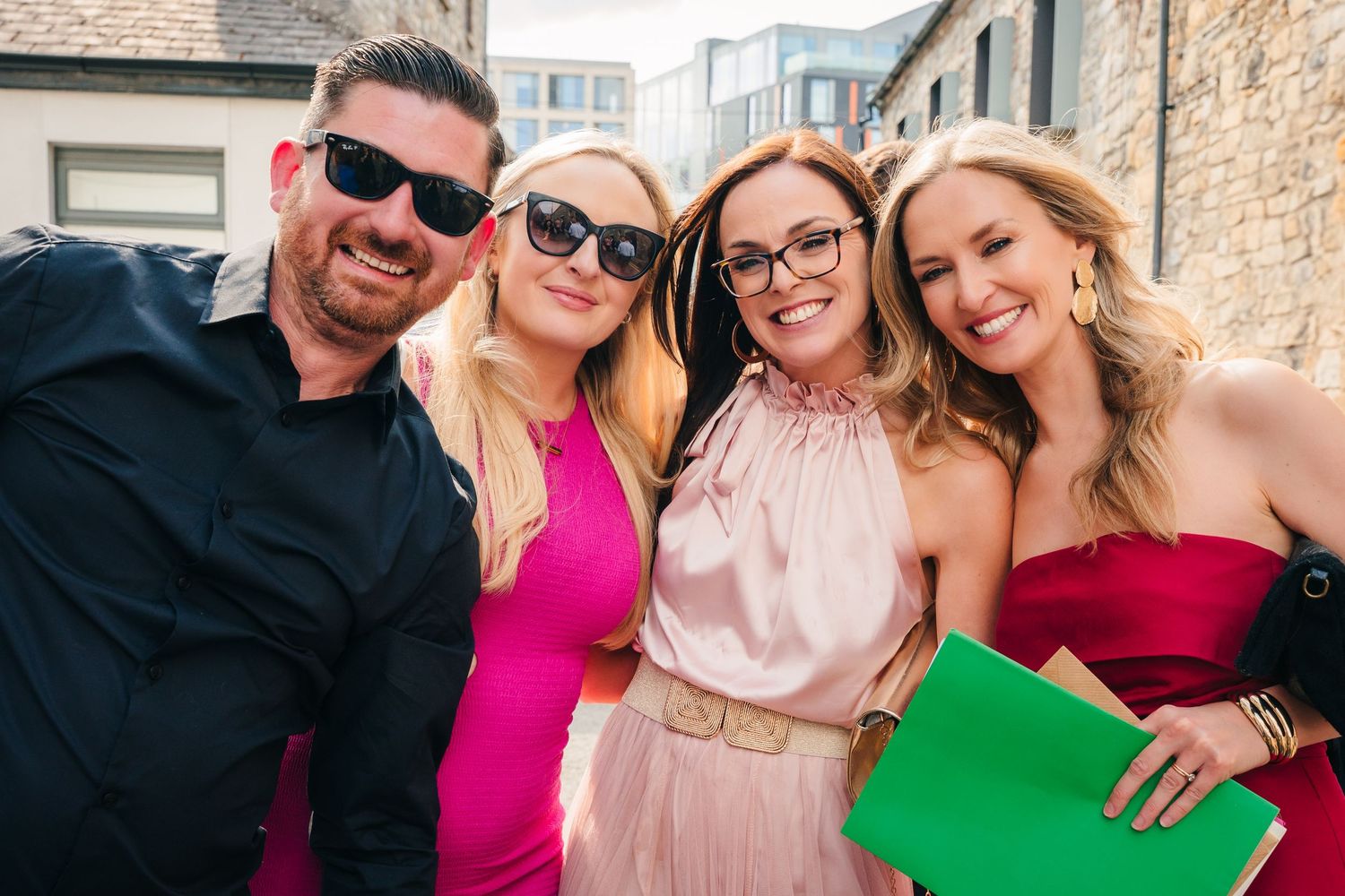 A group of wedding guests in colorful attire posing together for a photo outdoors. Same sex wedding PHOTOGRAPHER Dublin
