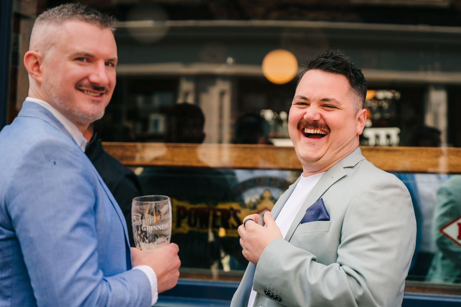 Wedding guests enjoying drinks and laughter at an outdoor celebration. Same sex wedding PHOTOGRAPHER Dublin