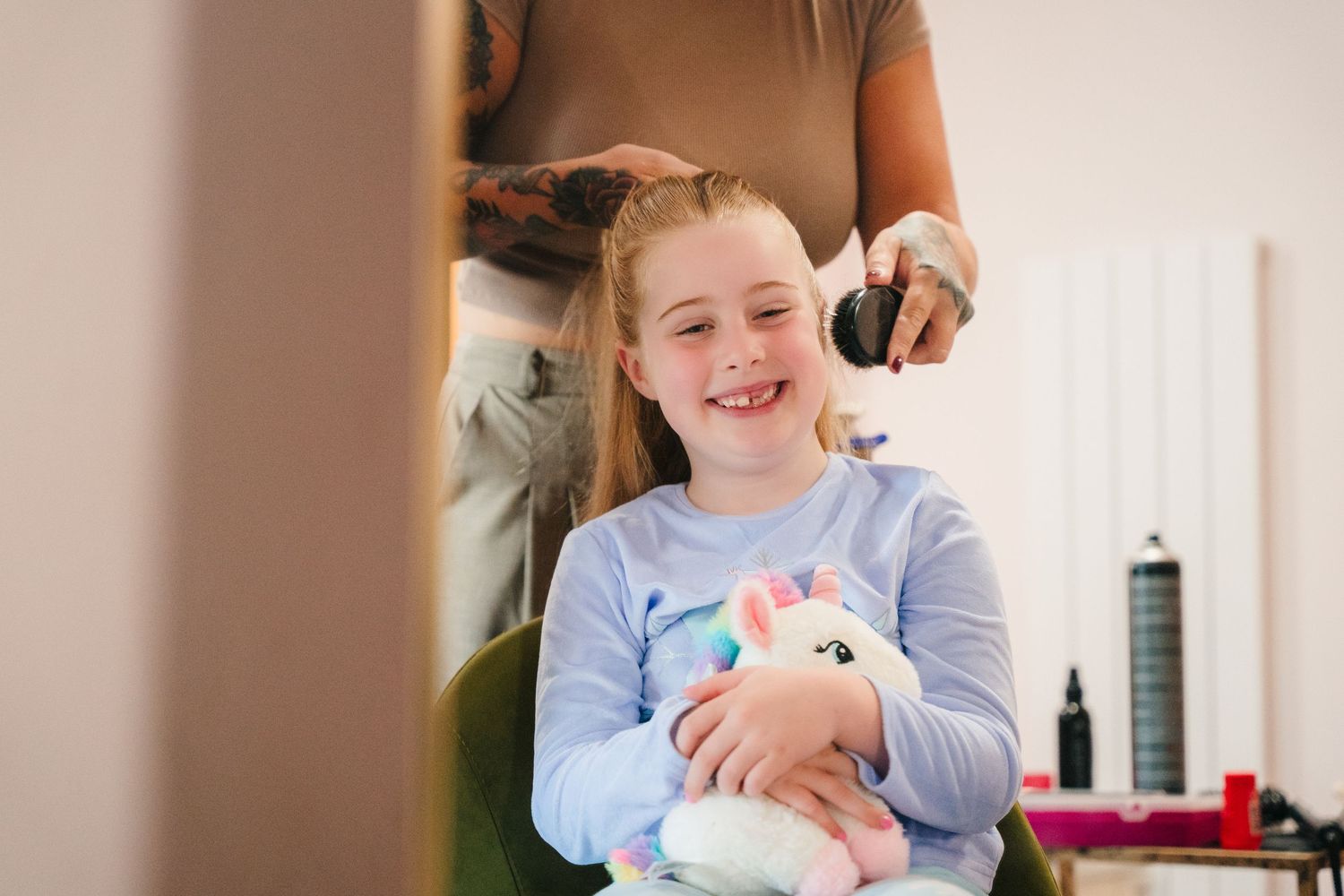 Child laughs while holding a small white stuffed animal on a couch indoors. Village Barn Tyrrellspass wedding photographer Ireland