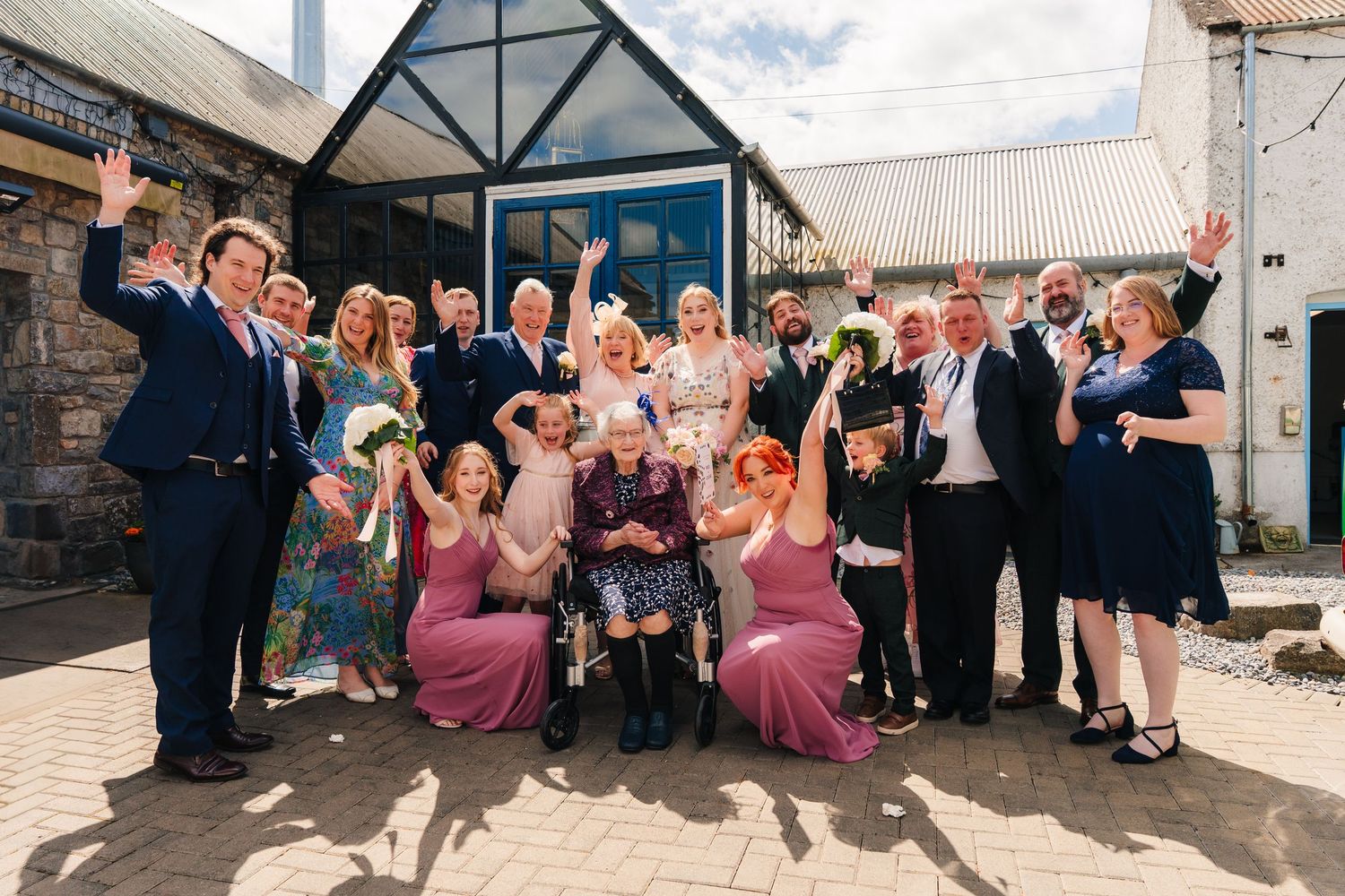 Wedding party and guests posing for group photos outside a rustic barn-style venue with timber framing. . Village Barn Tyrrellspass wedding